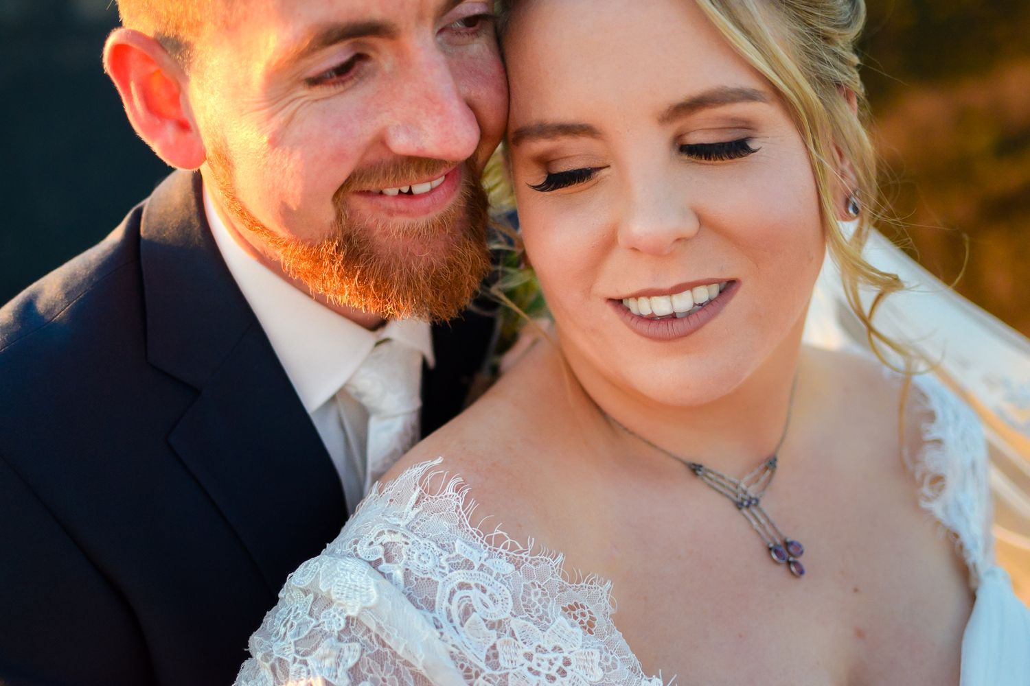 A close-up portrait of a happy couple on their wedding day in warm autumn lighting.
