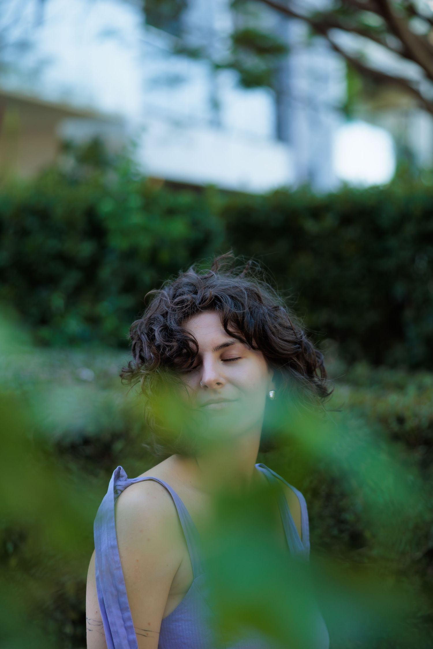 An artistic portrait framed by green foliage with soft focus.