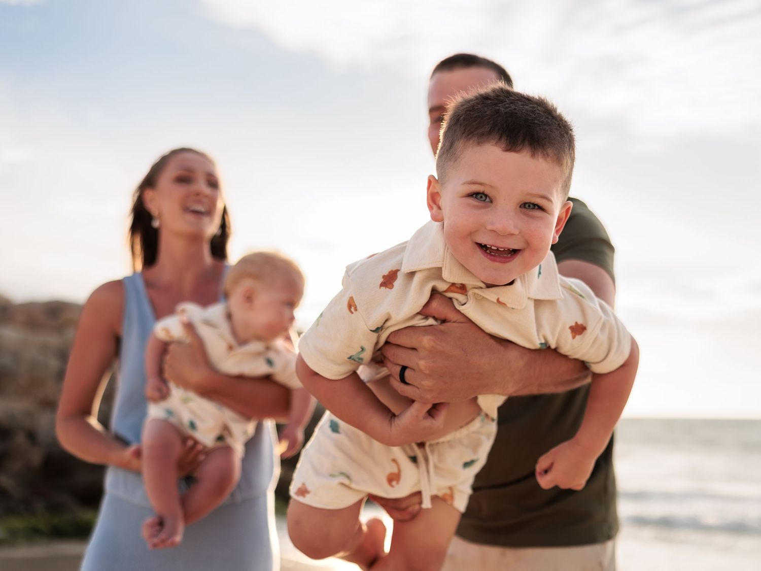 A series of joyful beach moments showing parents lifting and playing with small children at sunset by the ocean.