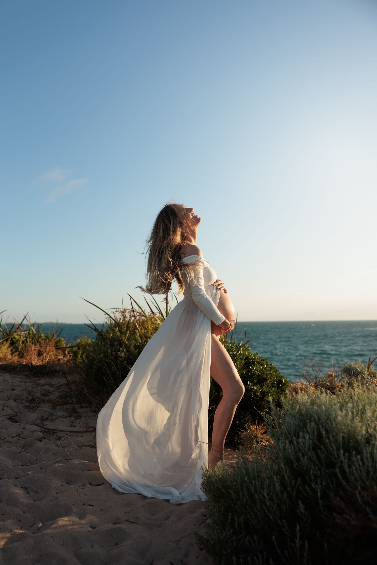 A series of sunset beach photos showing a flowing white dress moving in the ocean breeze against a coastal backdrop.