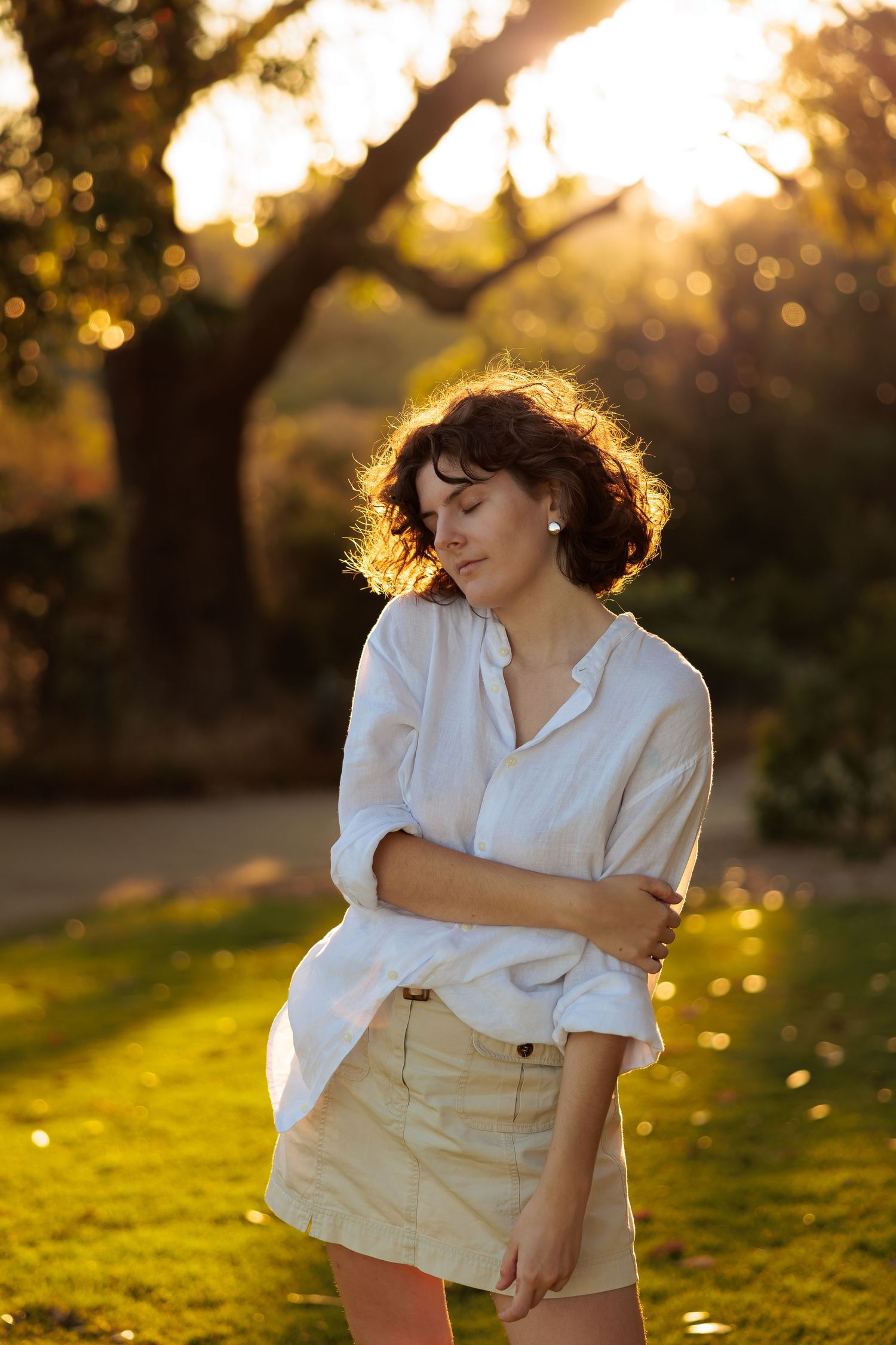 A dreamy golden hour portrait series of someone in a white shirt and beige pants against a sunlit grassy background.