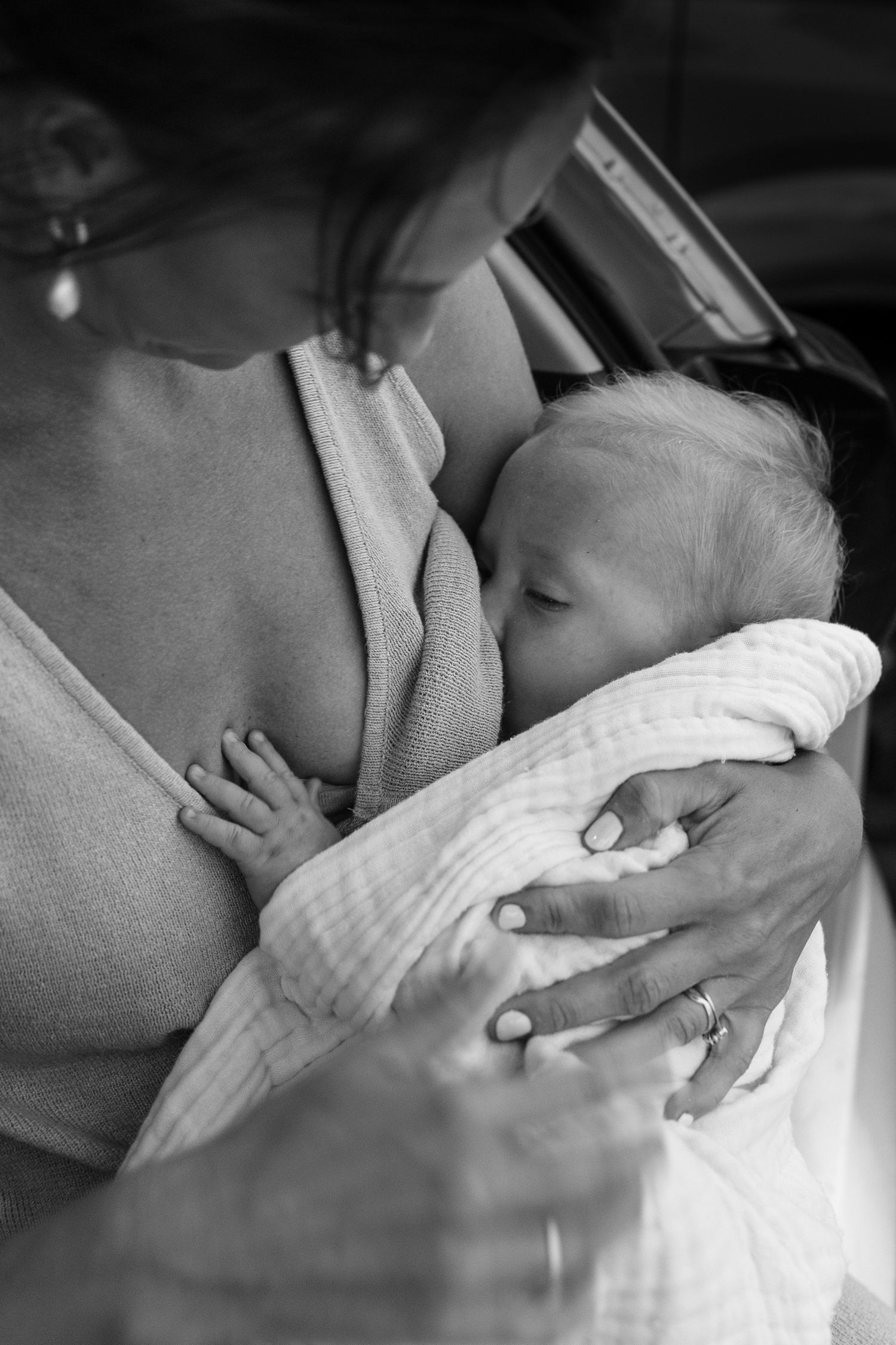 A tender black and white photo series showing a newborn baby being cradled and bonding with their parent.