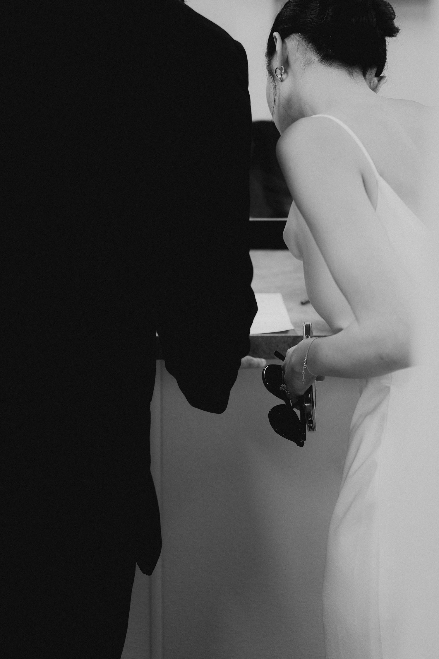 Black and white photo of bride in white gown standing beside groom.