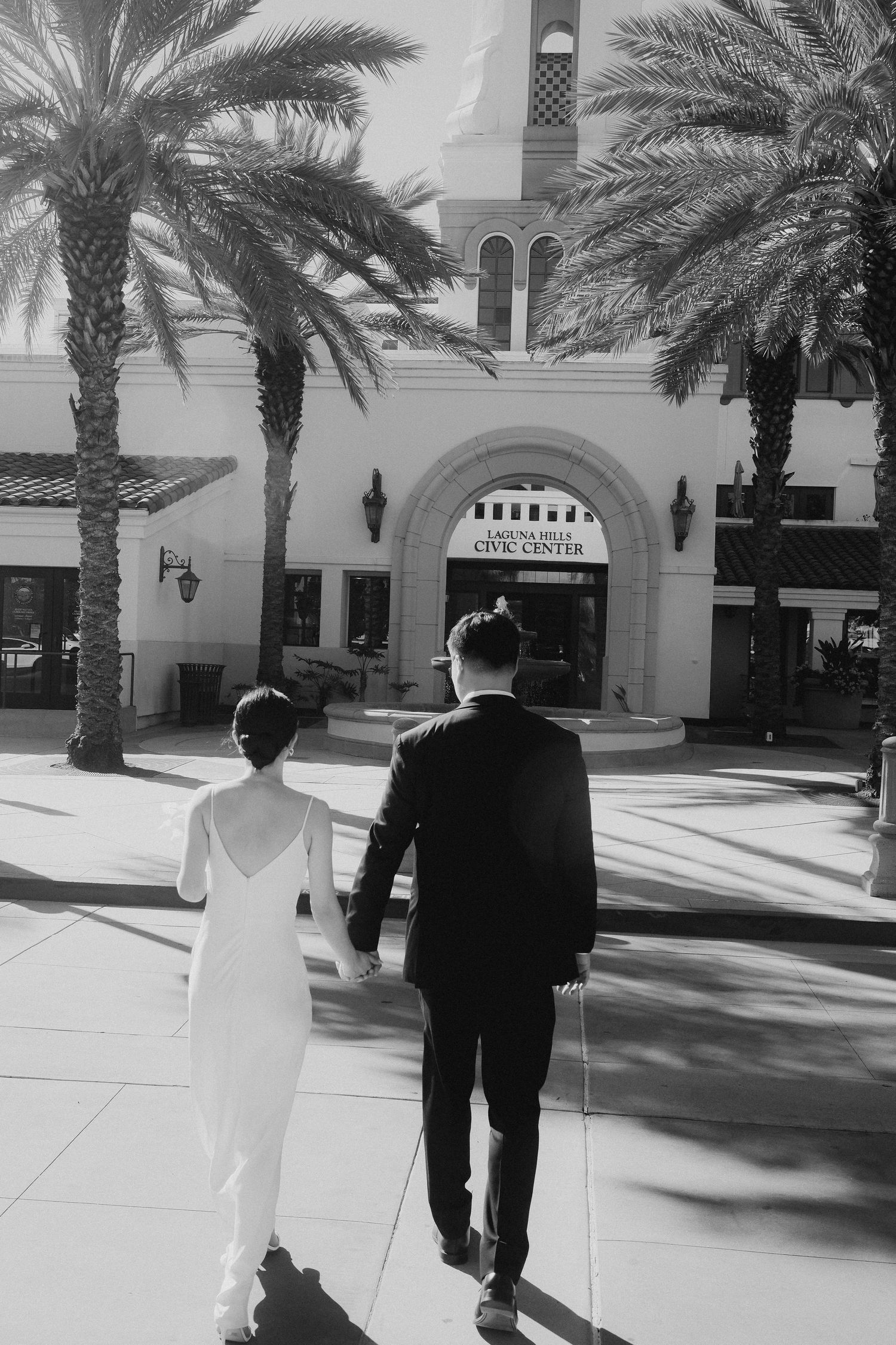 Black and white photo of newlyweds holding hands at Laguna Hills Civic Center.