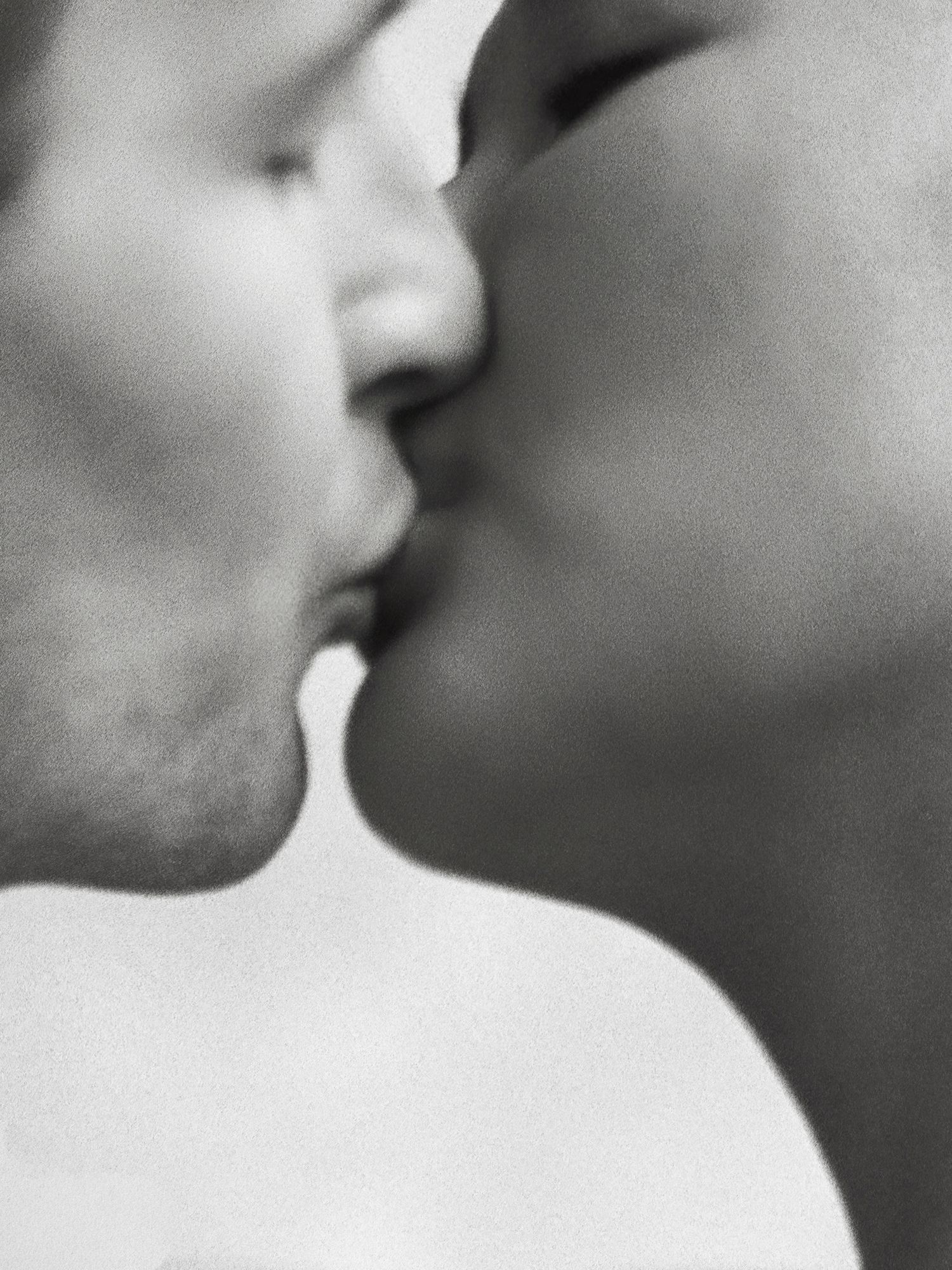 A close-up black and white photo capturing a tender kiss between a bride and groom on their wedding day.