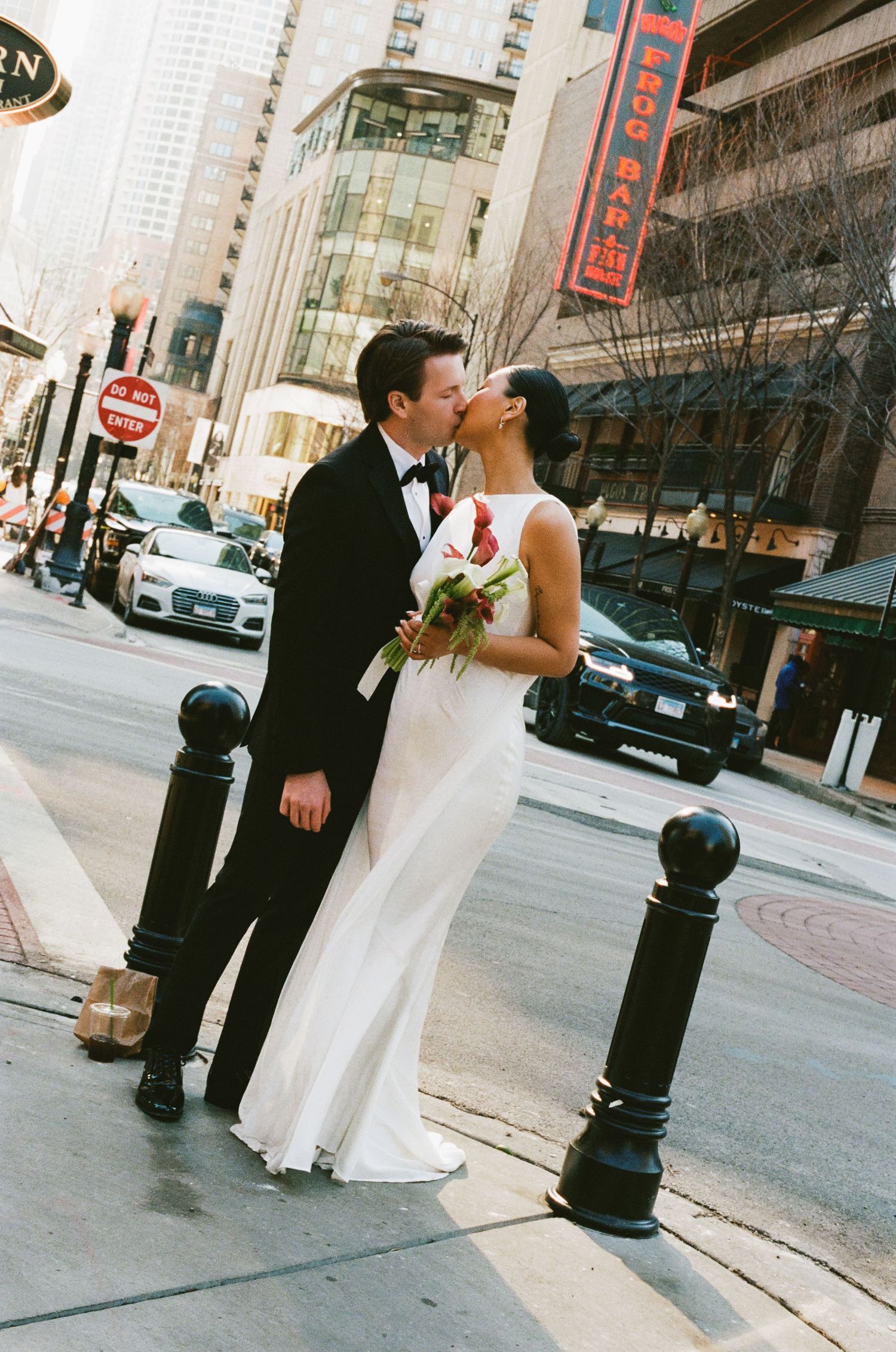 Bride and groom share a kiss on a sunny Chicago street corner near Frog Bar and Gibsons Steakhouse.