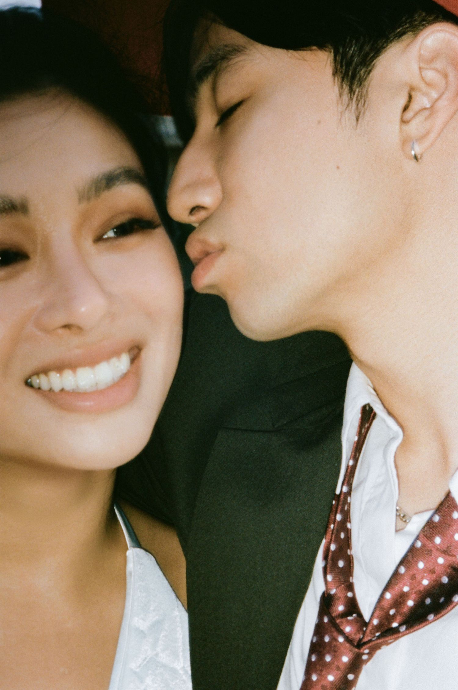 Close-up of couple sharing a kiss, man in white shirt and polka dot tie.