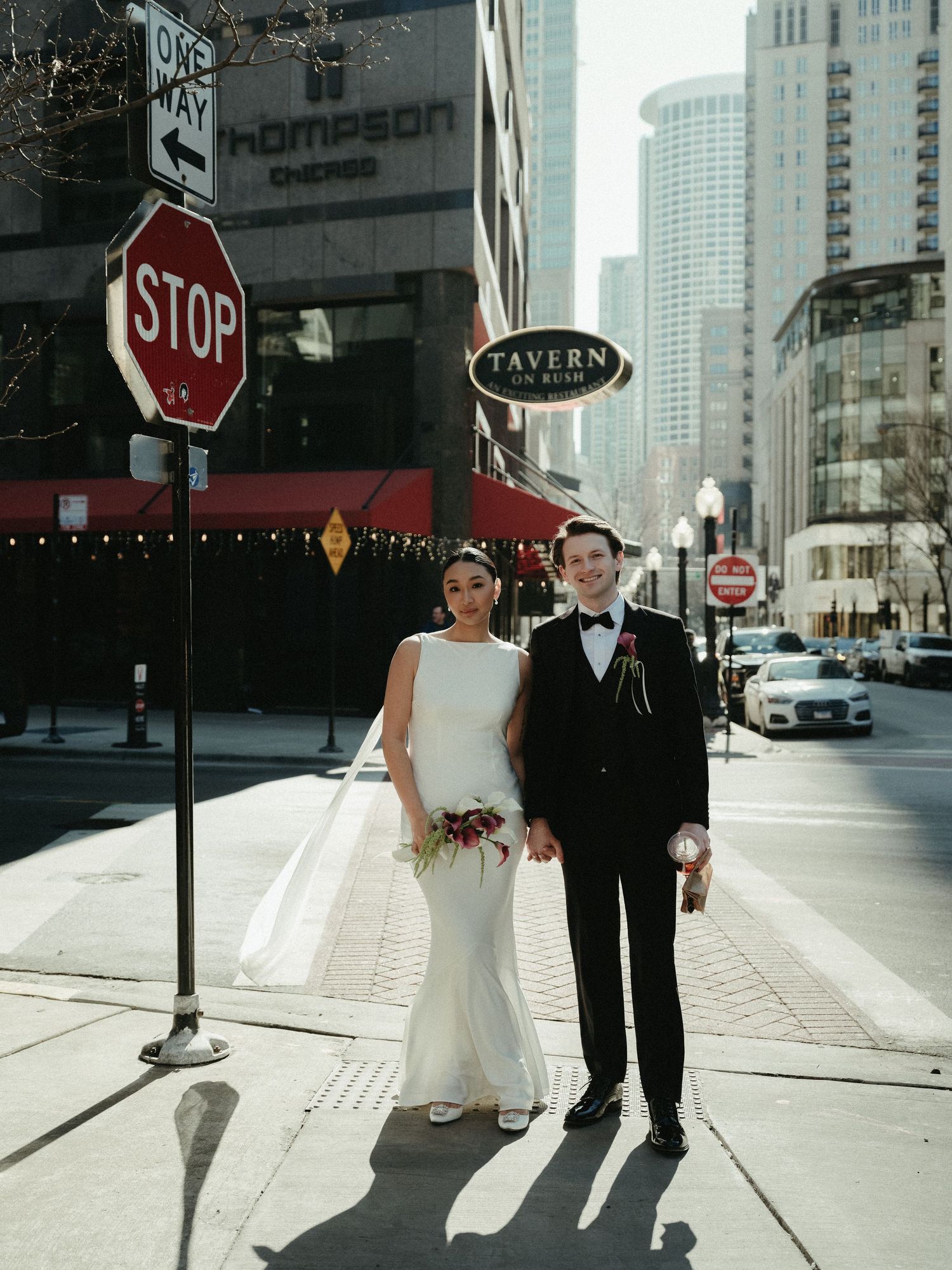 Bride and groom pose near a STOP sign outside Thompson Chicago hotel and Tavern on Rush.