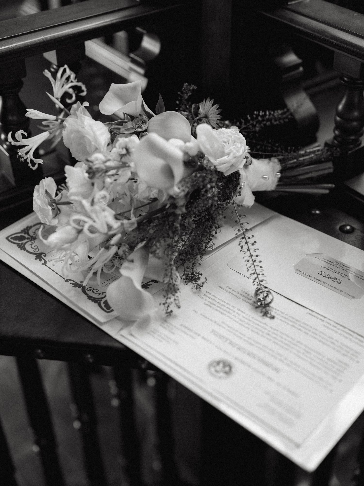 Black and white photo of bridal bouquet resting on official marriage certificate.