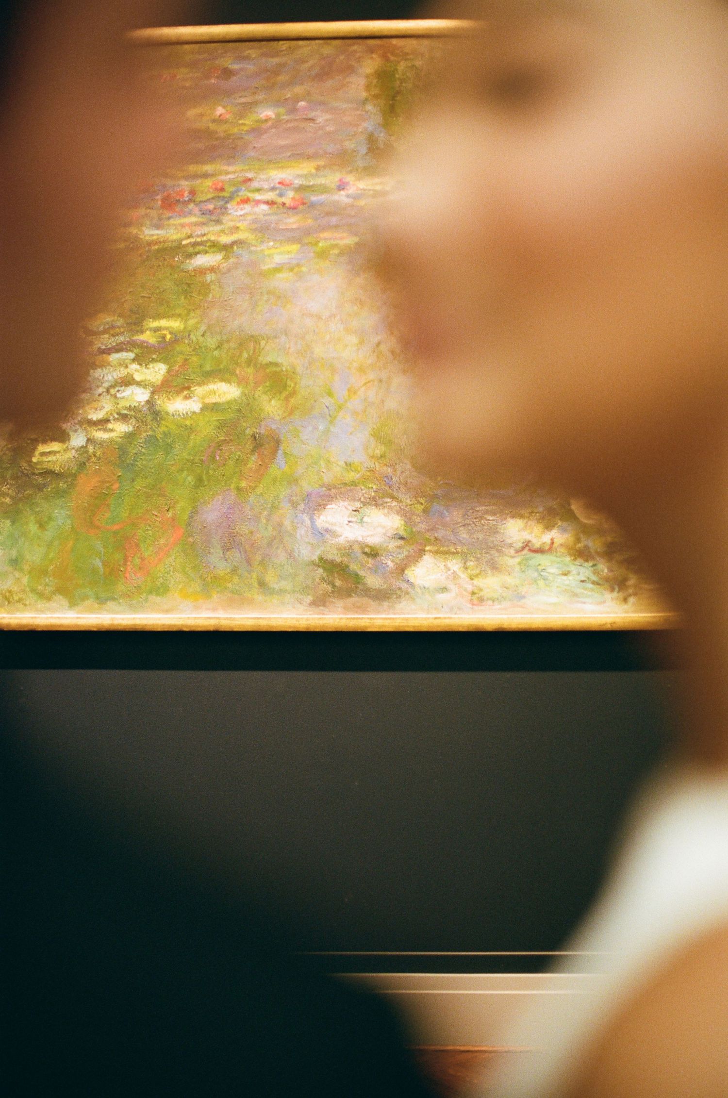 Bride gazes at a colorful Monet water lilies painting in a museum gallery on her wedding day.