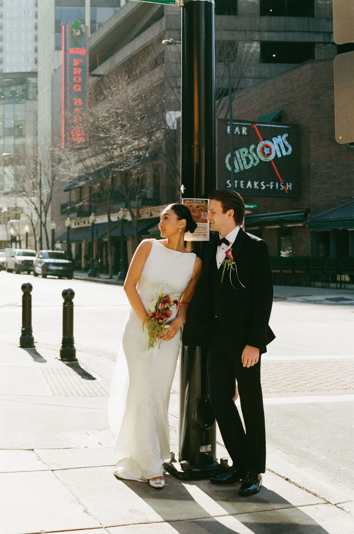 Bride and groom share a romantic moment on a sunny Chicago street corner near Gibsons Bar and Steakhouse.