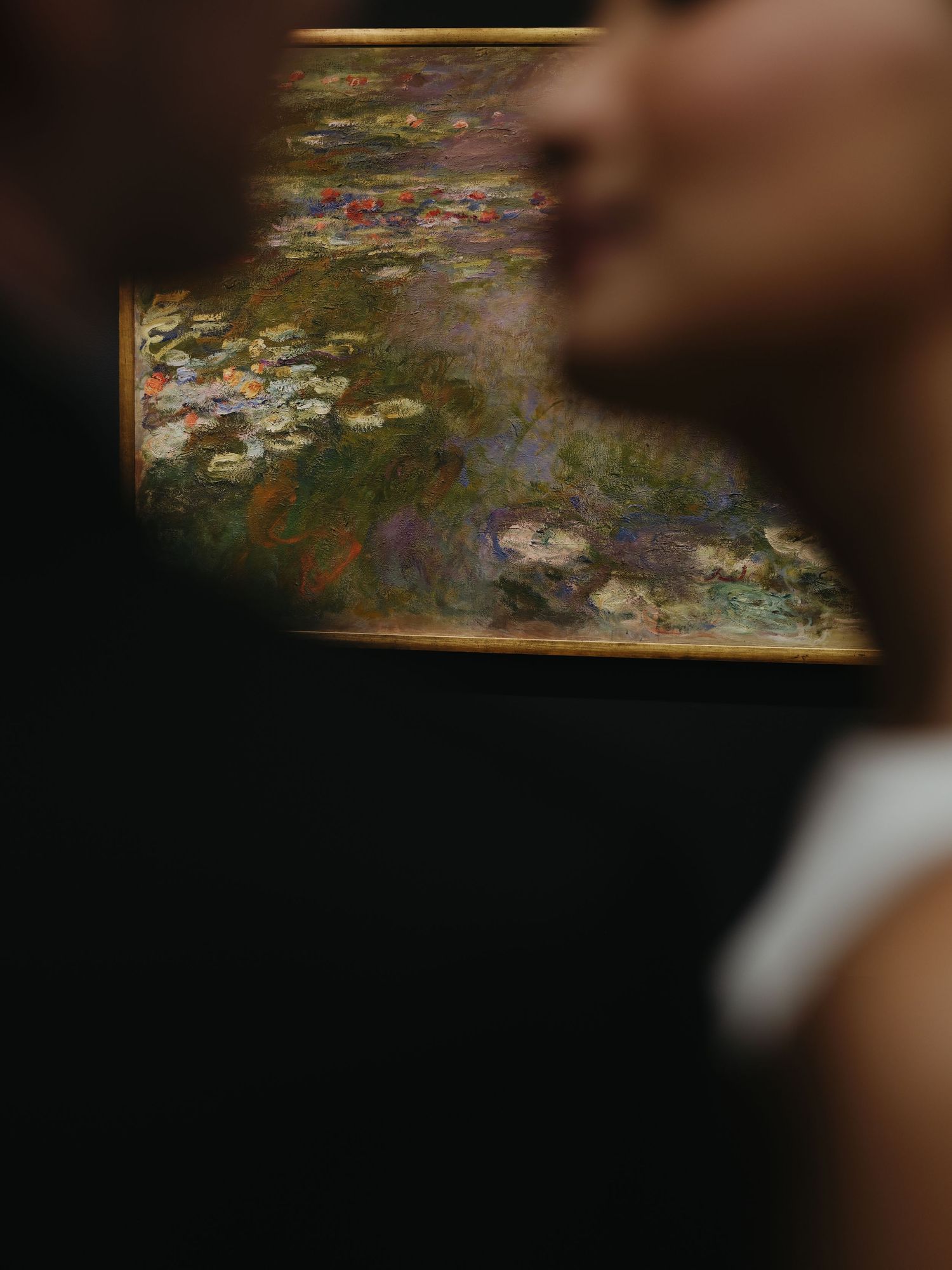 Couple standing close before a colorful Impressionist water lilies painting in a museum gallery.