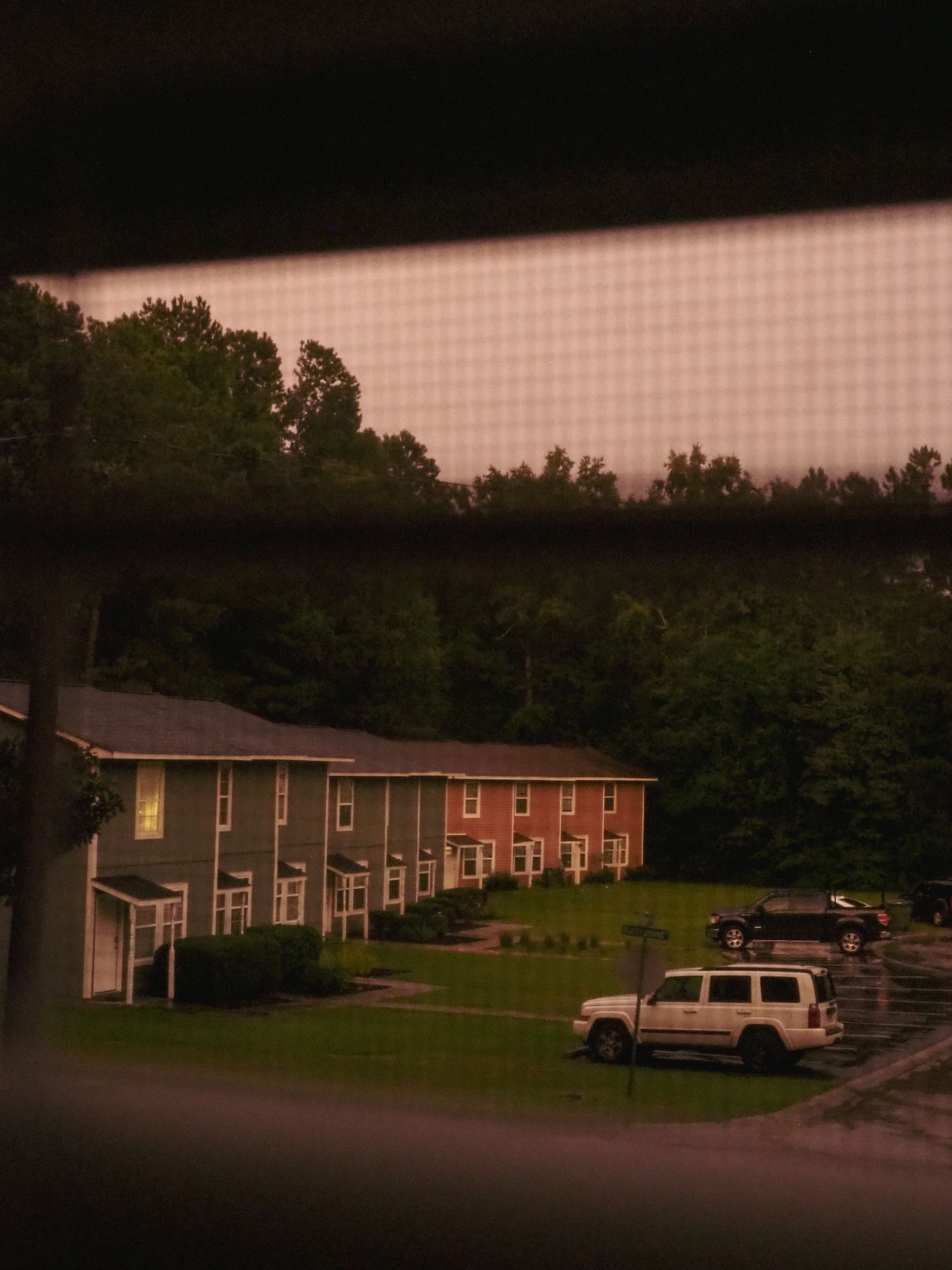 Row of townhouses at dusk with cars parked along a quiet residential street.
