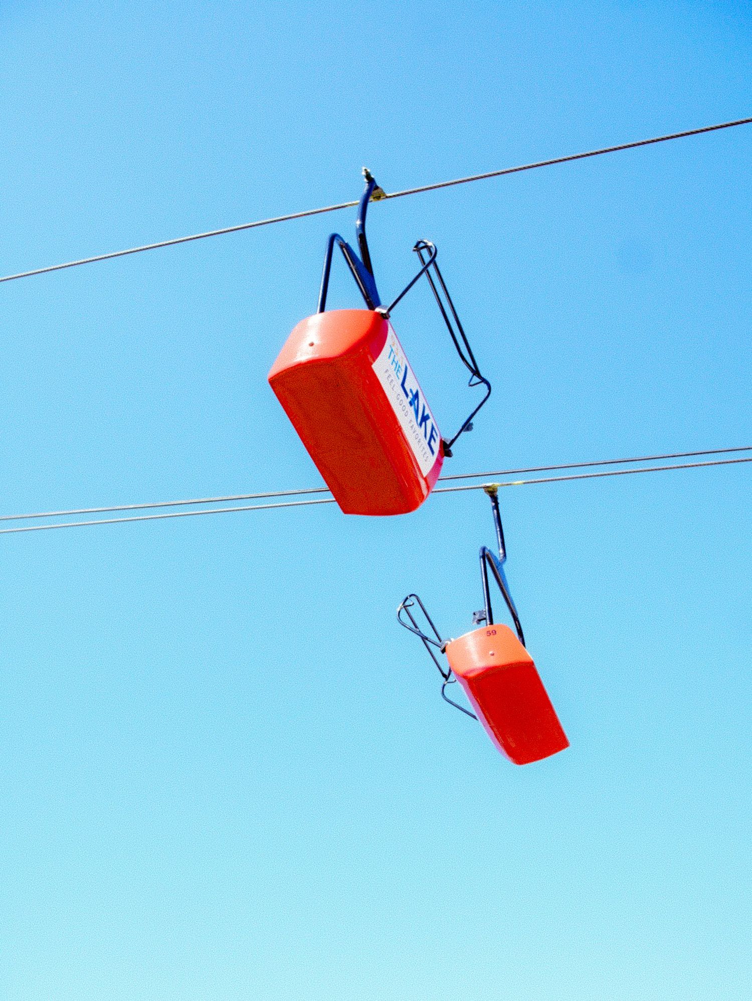 Red cups dangle from wires against a bright blue sky.