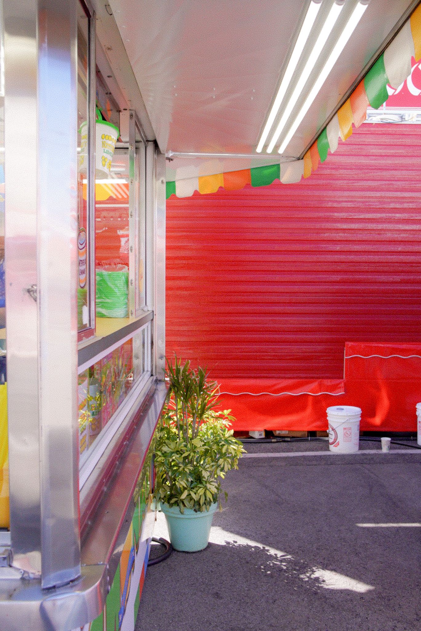 Red shutters and colorful decorations line an indoor space with gray flooring and fluorescent lighting.