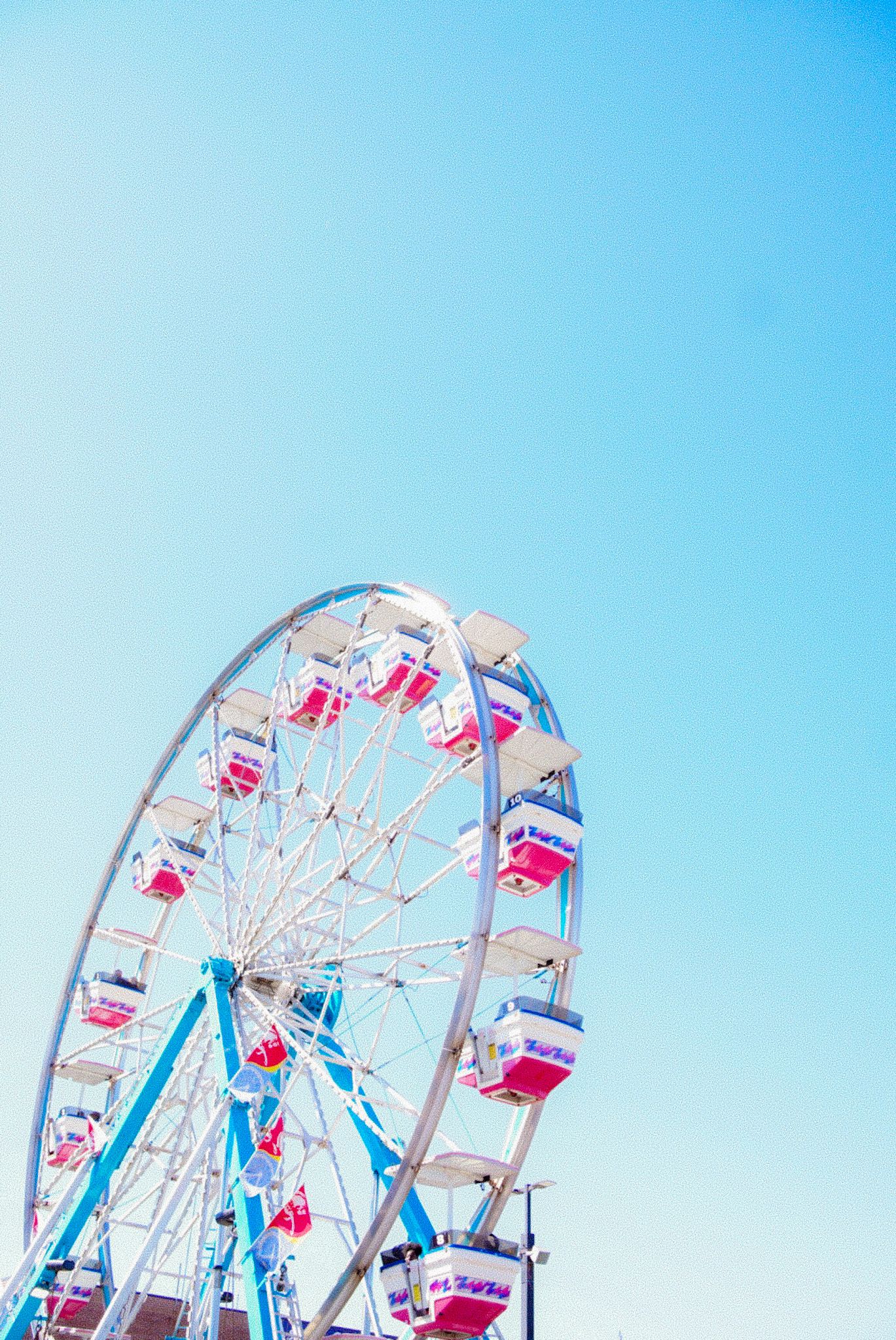 A white and red ferris wheel stands against a clear blue sky.