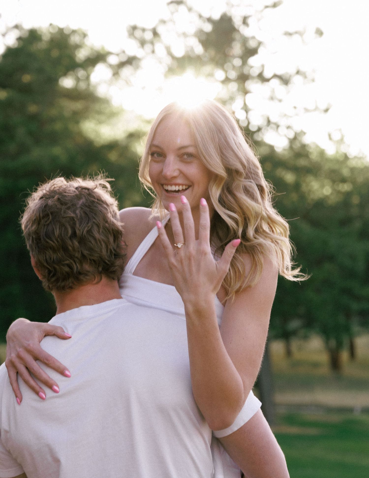 Ben and Renee laughing together in a golden field at sunset in evergreen Colorado
