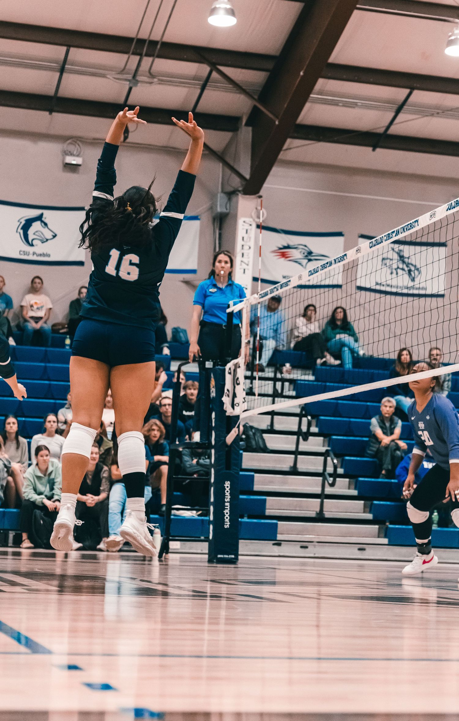 Colorado Christian University volleyball player #16 jumping in the air after hitting the ball