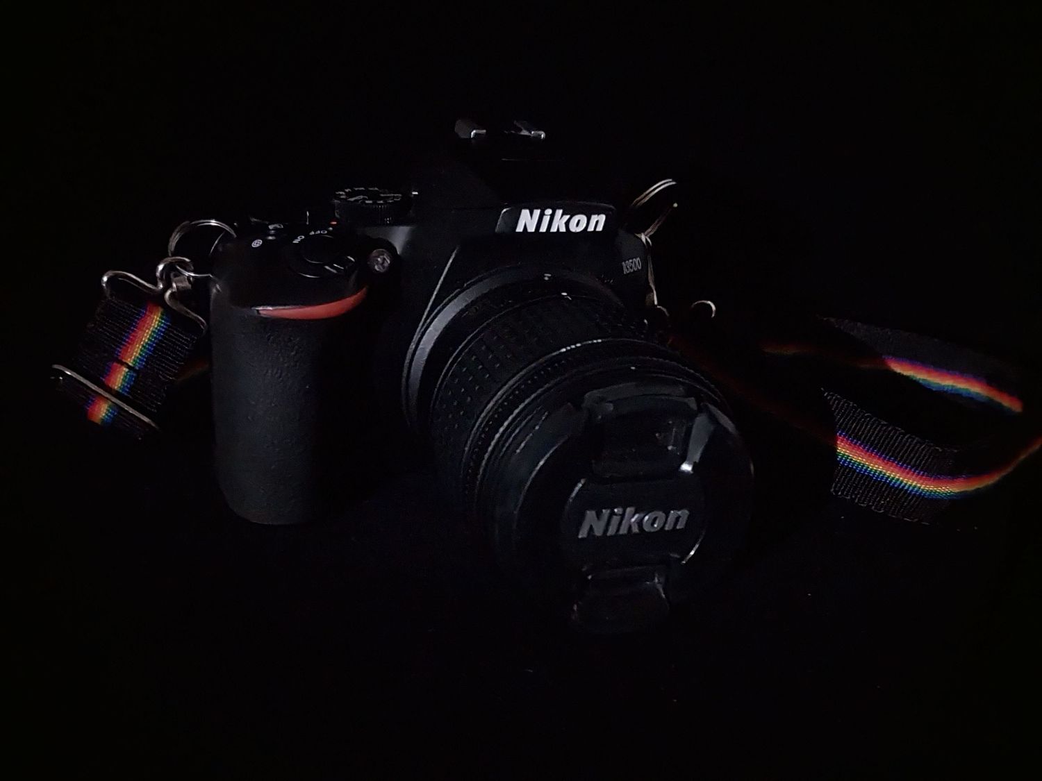 My Nikon DSLR camera with lens sits in dramatic low-key lighting against a dark background.