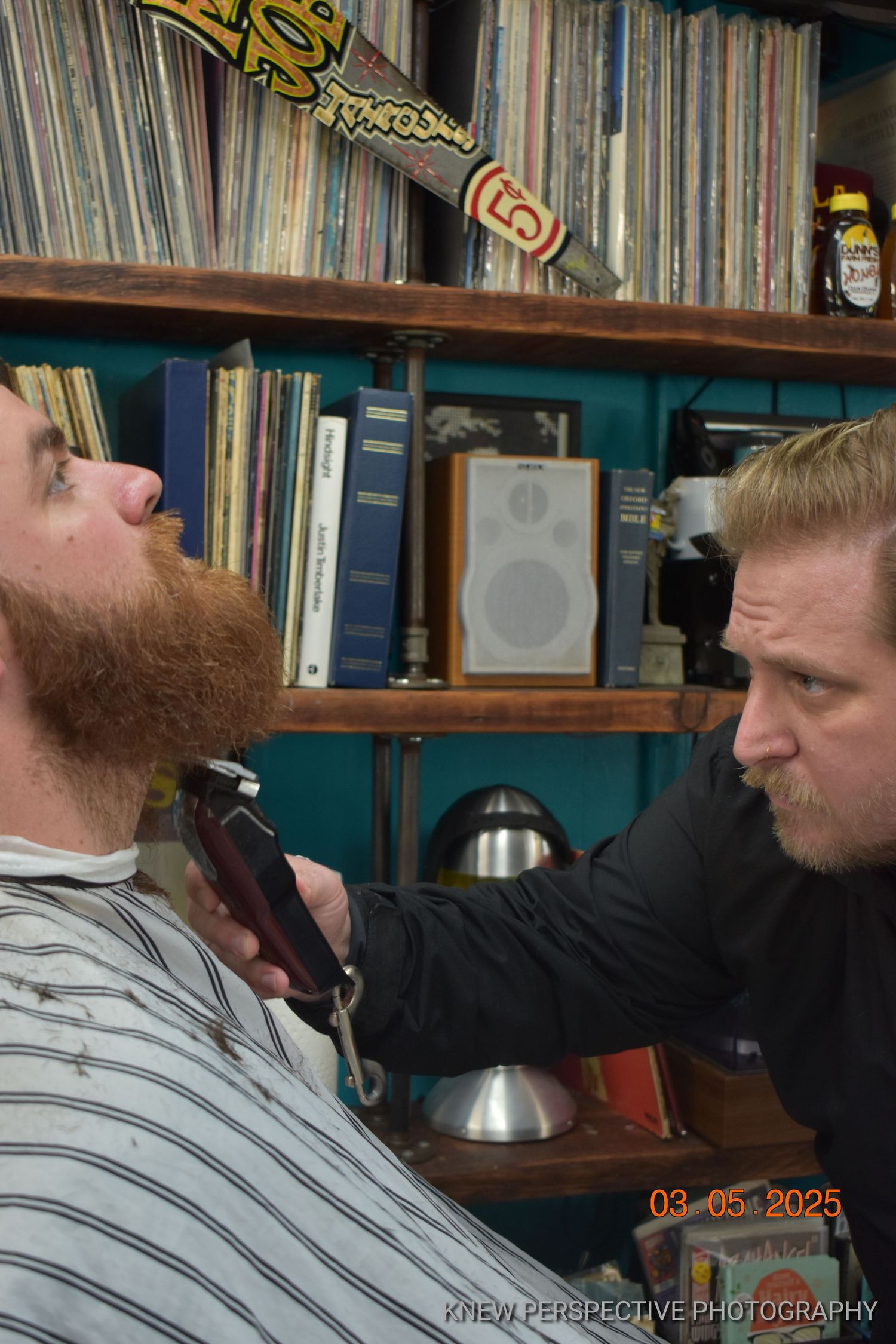 A barber deeply focused on a beard trim.