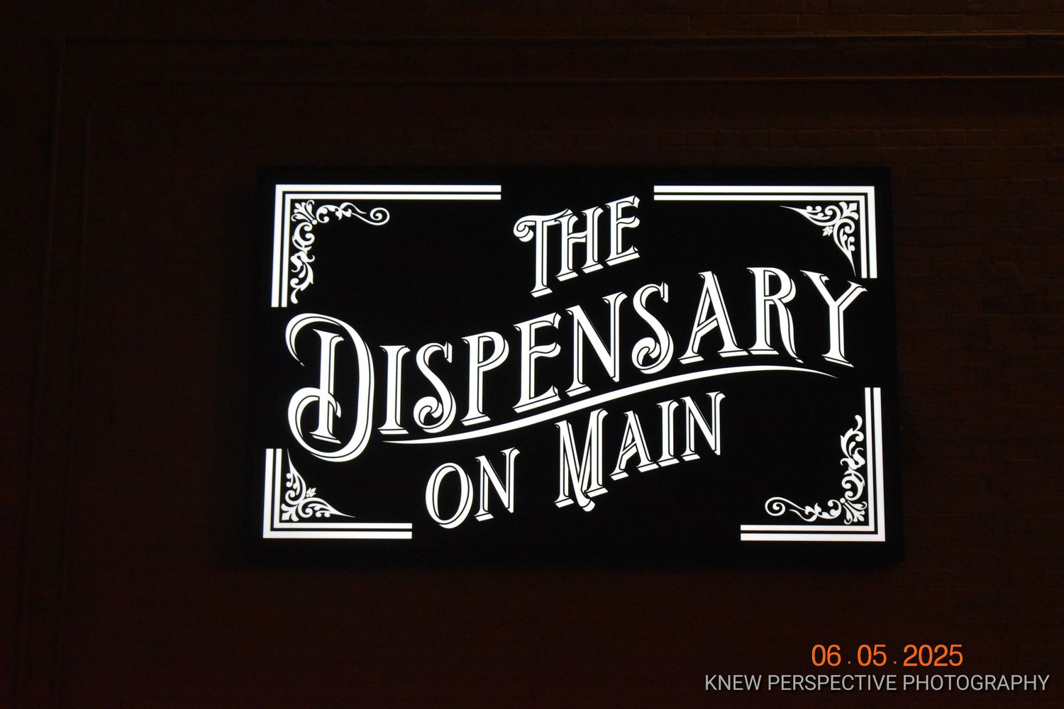 Decorative vintage-style text signage with ornate borders and flourishes displayed against a dark background.