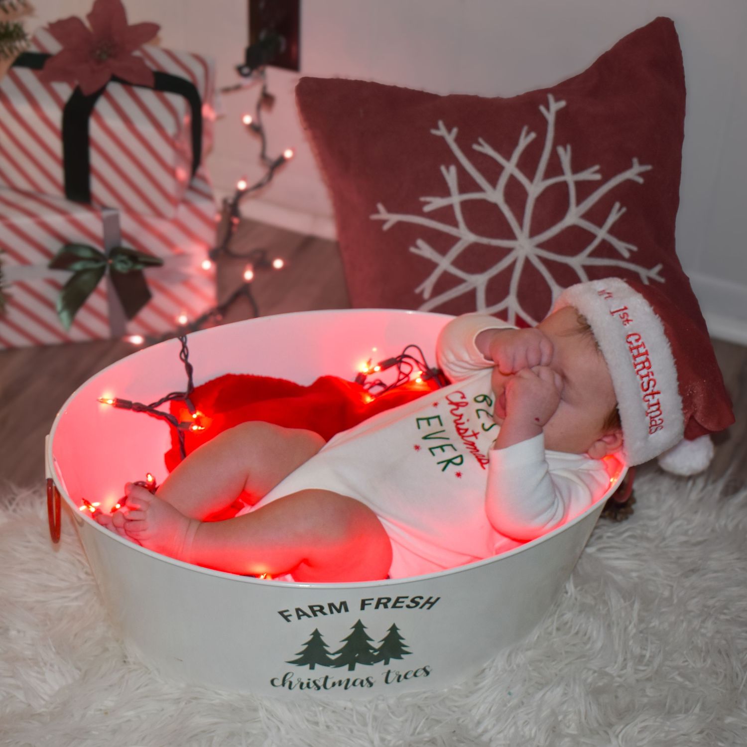 Red string lights illuminate a cozy display of a sleepy baby.