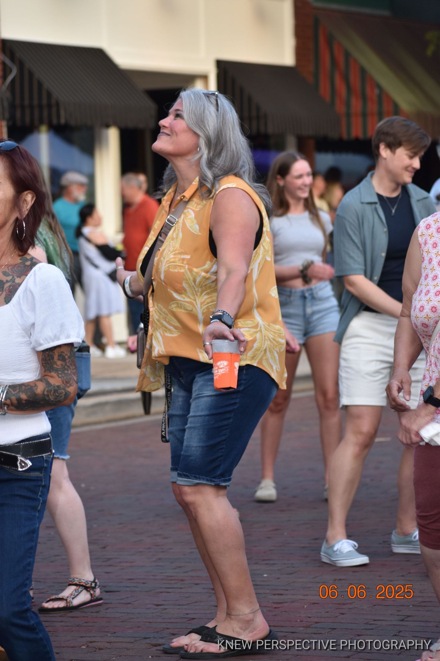 People enjoying a summer day on a crowded street with shoppers wearing casual clothing and shorts.