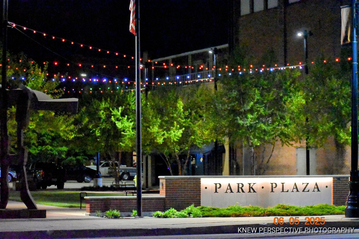Illuminated walkway at Park Plaza with string lights and landscaping at night creating an inviting atmosphere.