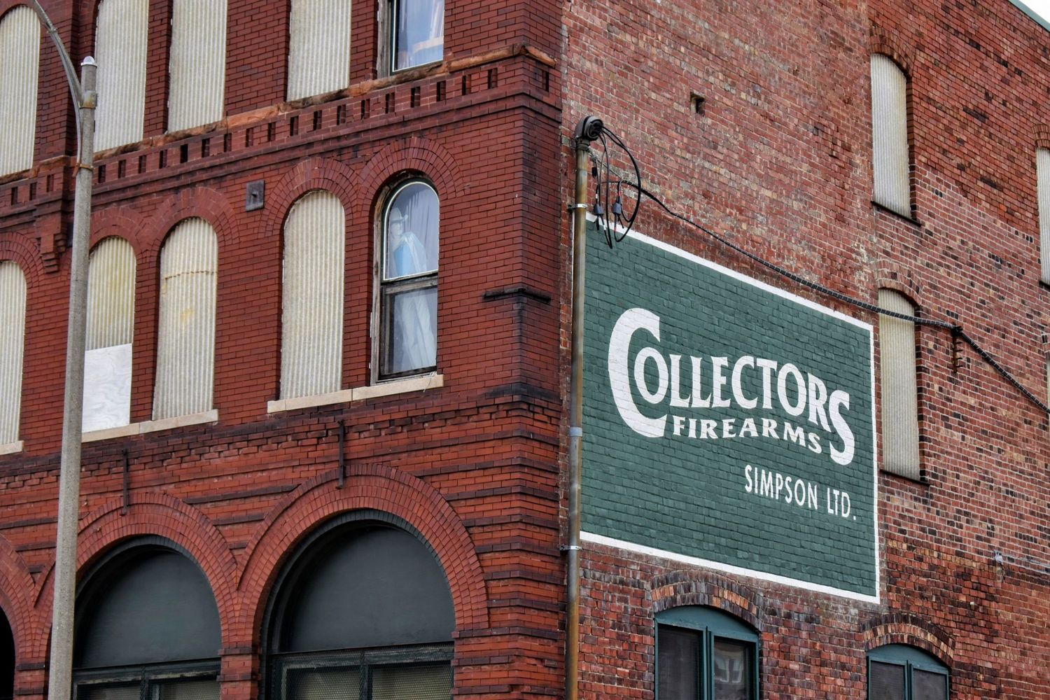 Historic red brick building with green 'Collectors' signage on the exterior facade and a cardboard cut-out of 