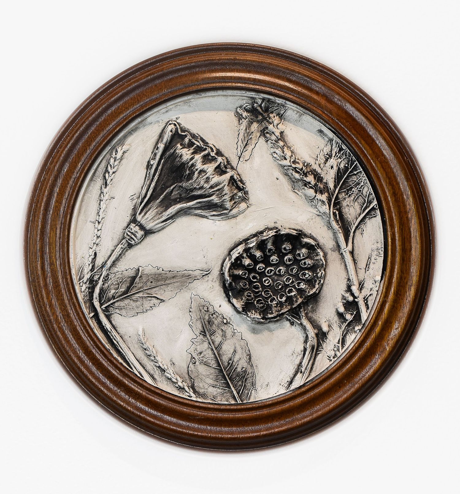 oval framed decorative wall art pieces featuring black and white botanical clay casting in wooden frame.