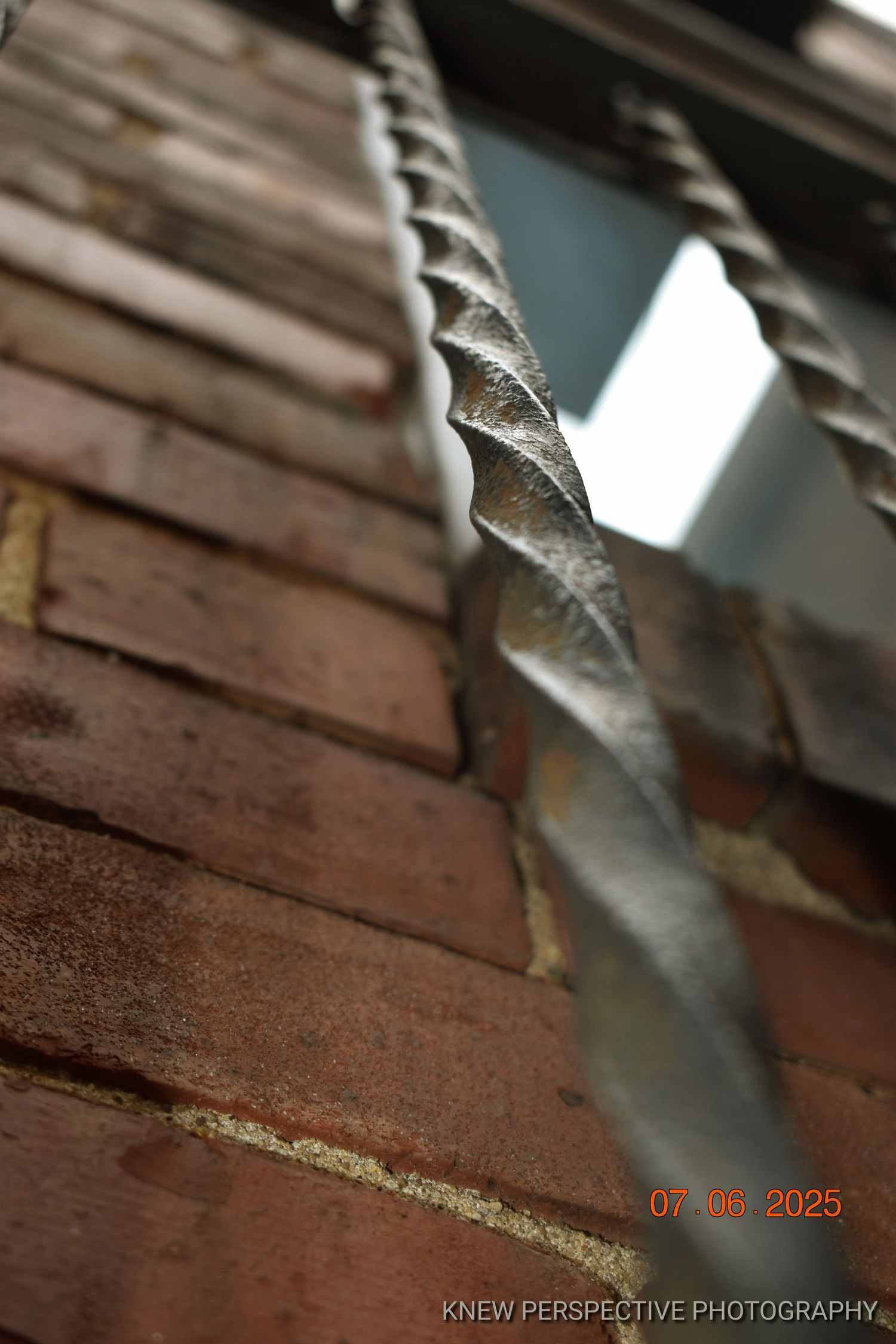 Close-up view of an Iron spindle against a brick wall.