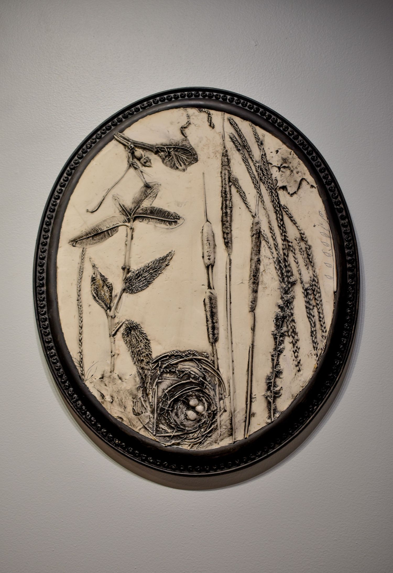 A decorative ceramic casting with black and white nature-inspired designs featuring birds nest and floral motifs.