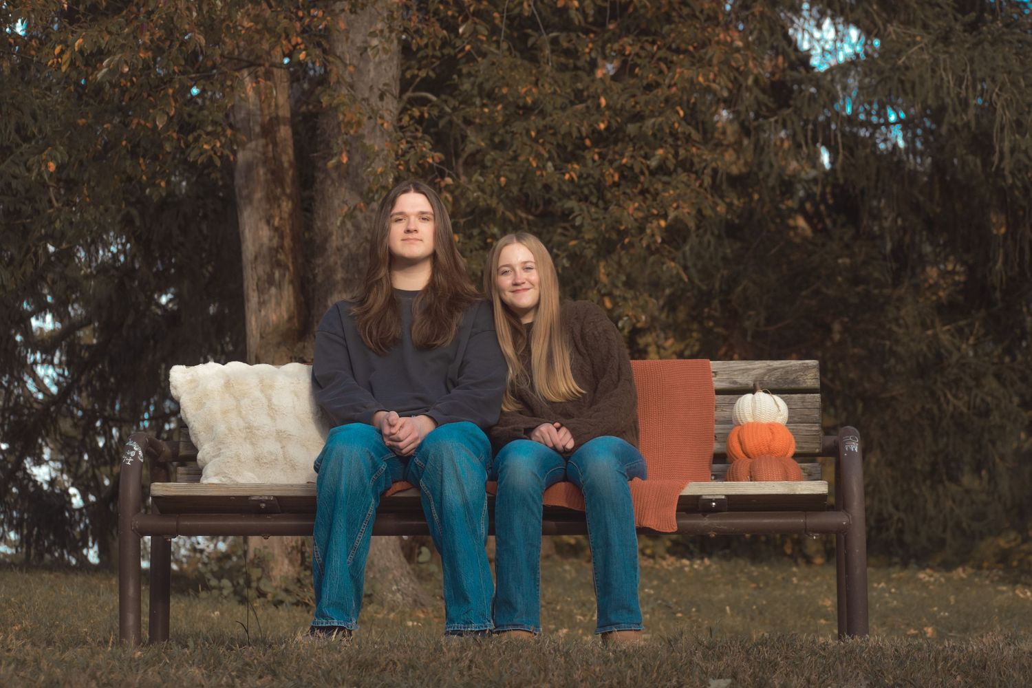 People sitting on wooden benches in a park surrounded by autumn trees during daytime.