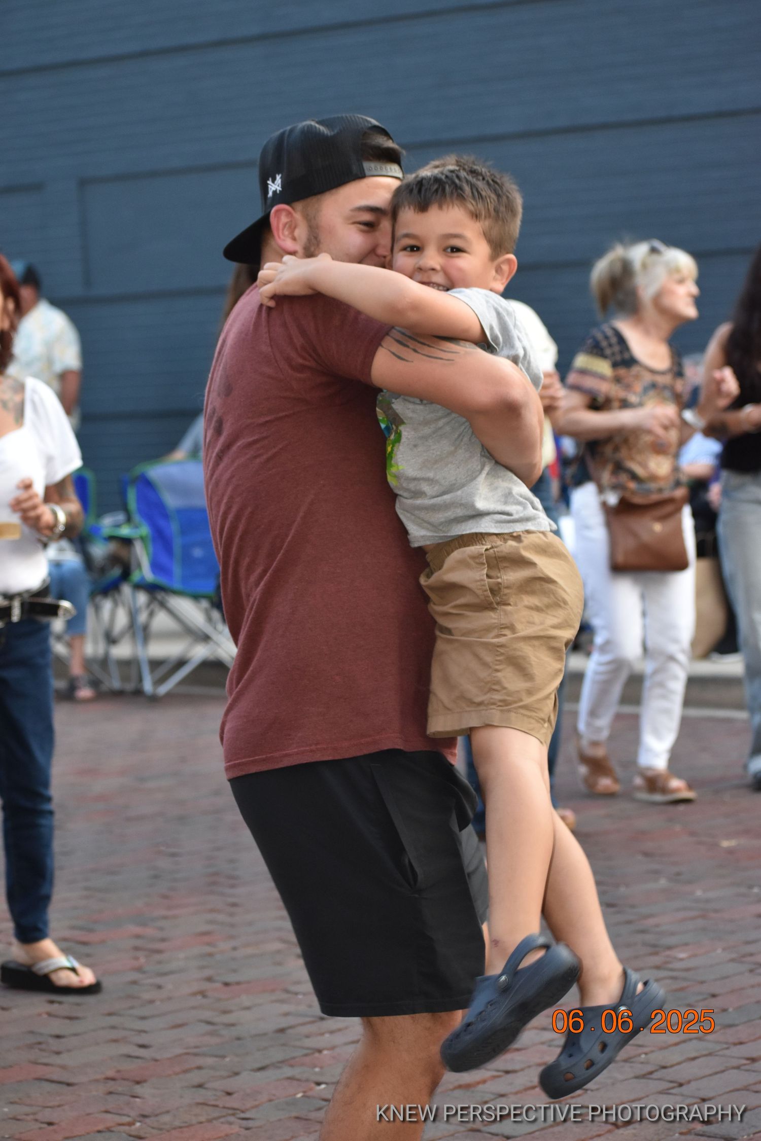 A tender moment shared between parent and child during a summer gathering on a brick road.