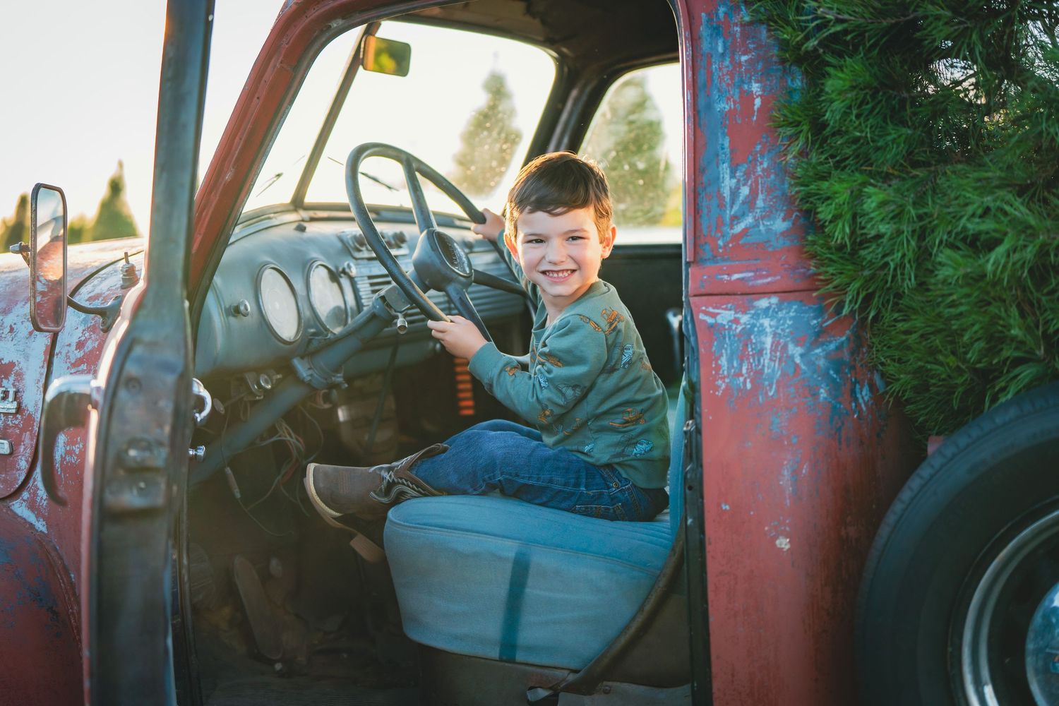 Vintage red truck with rustic patina parked in natural setting.