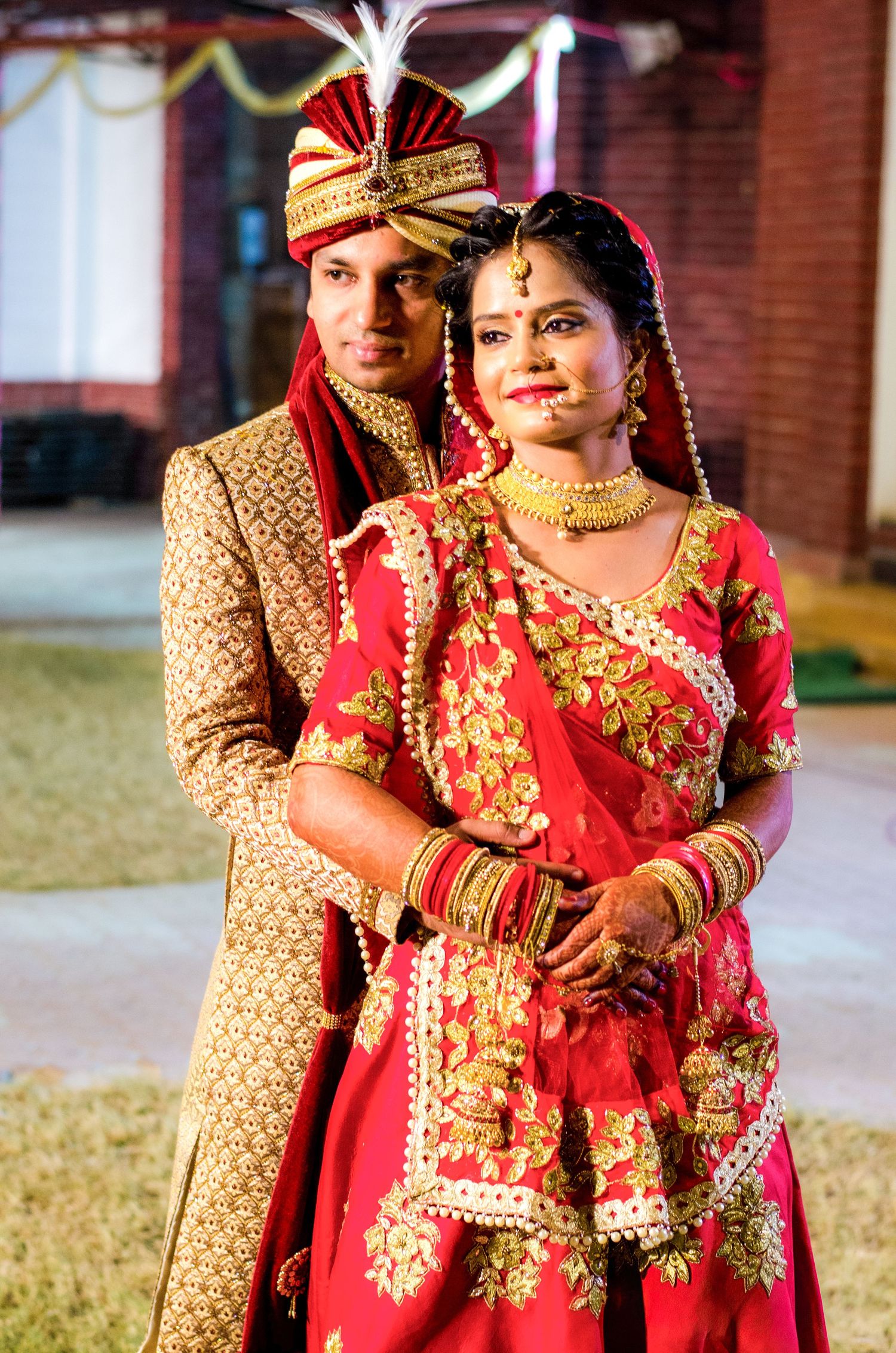 Couple in traditional Indian wedding attire walking together outdoors.