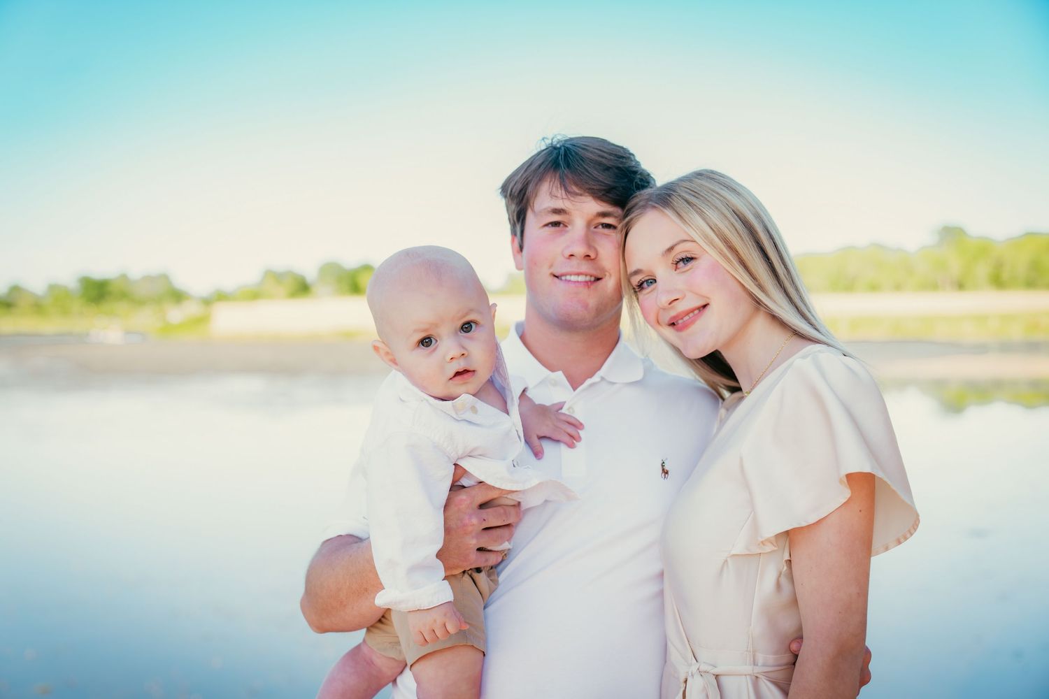 Family poses together by lake during sunset photo session.