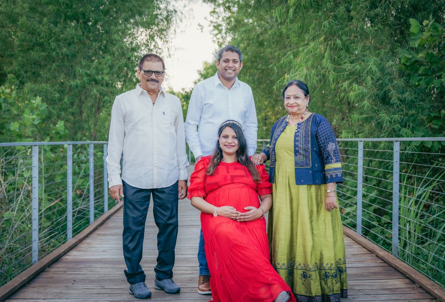 Family members stand together on a wooden walkway surrounded by greenery.