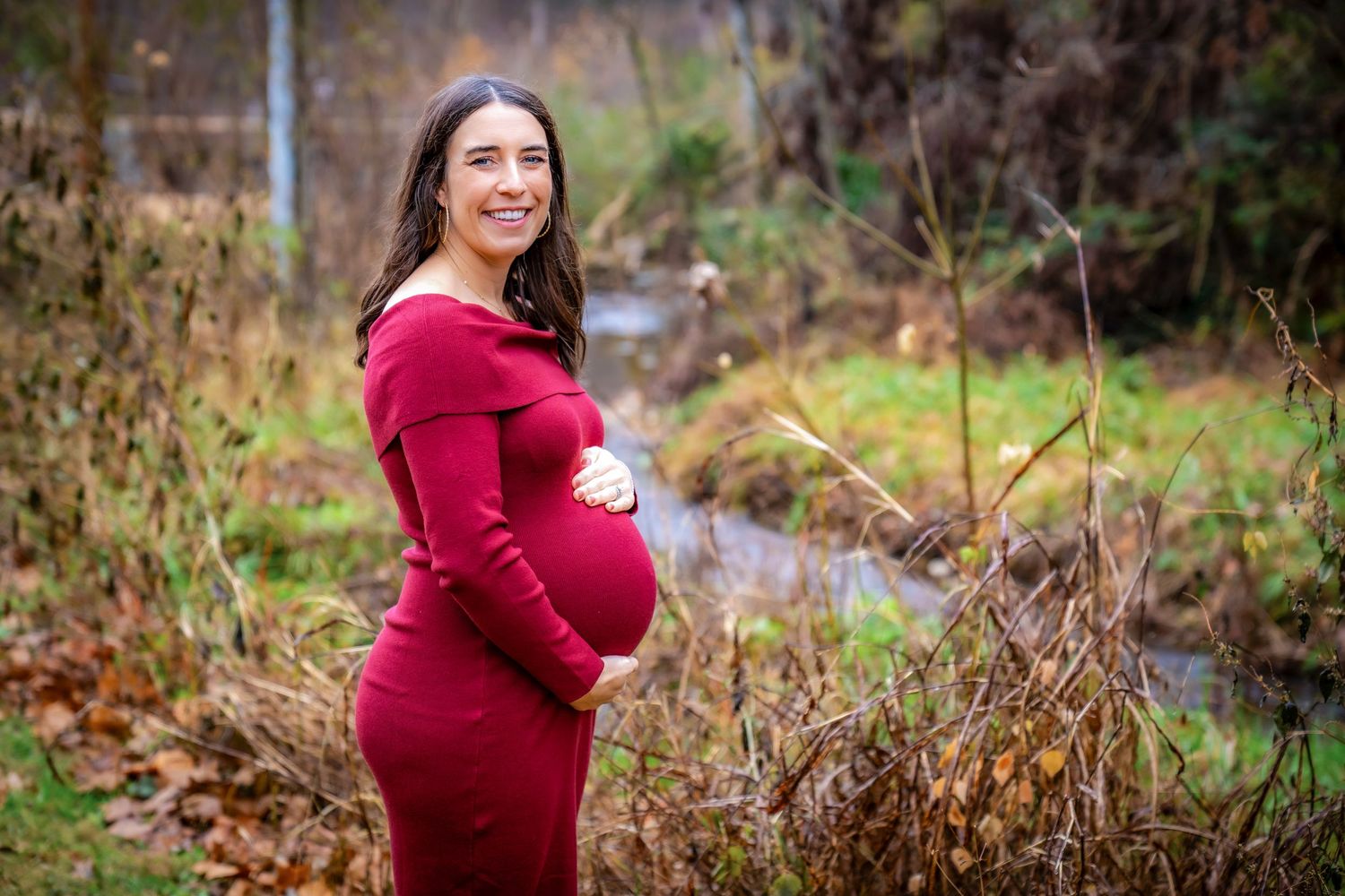 Maternity photos taken in a natural outdoor setting with fall foliage.
