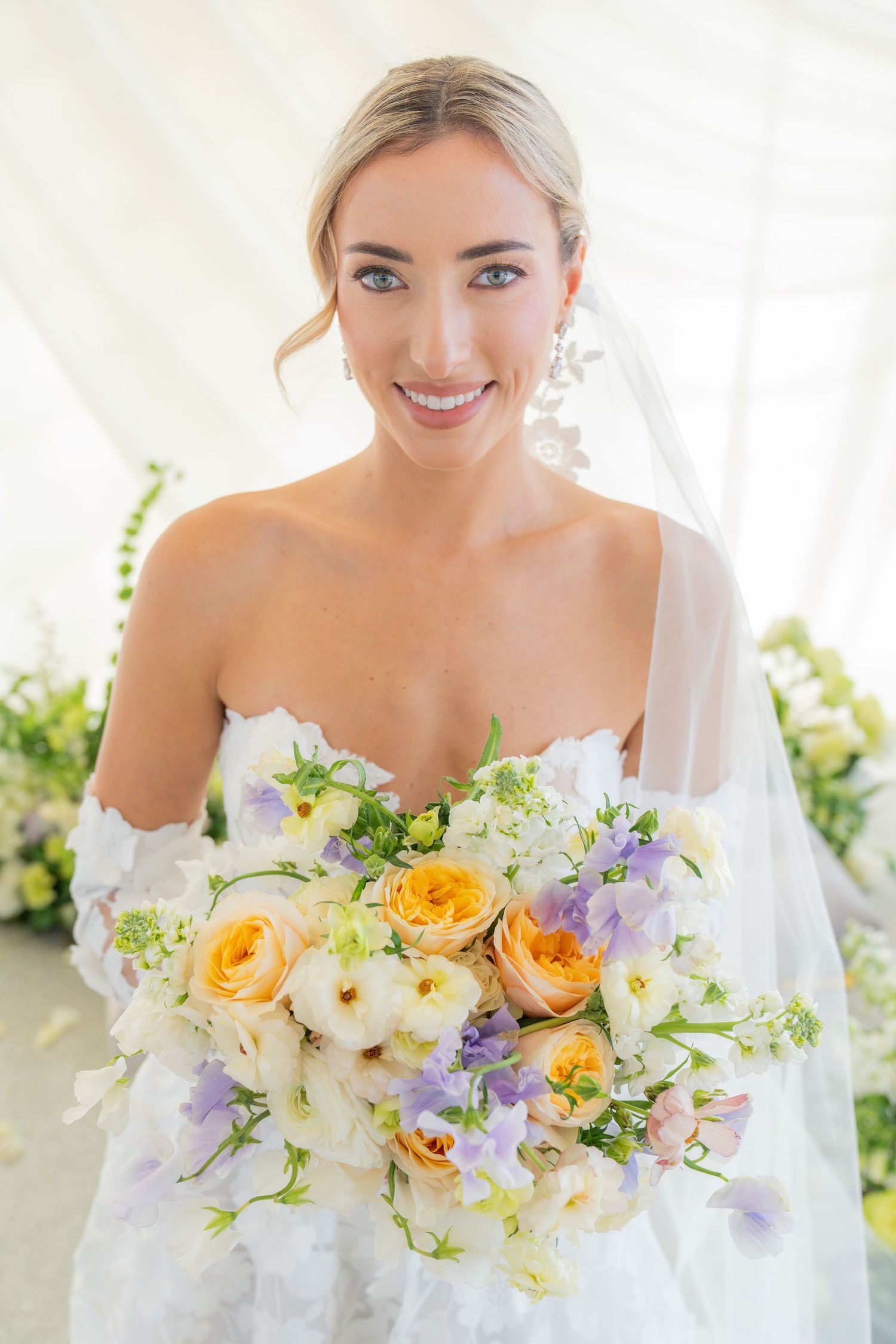 Close-up of spring wedding bouquet with yellow and purple flowers against white background.