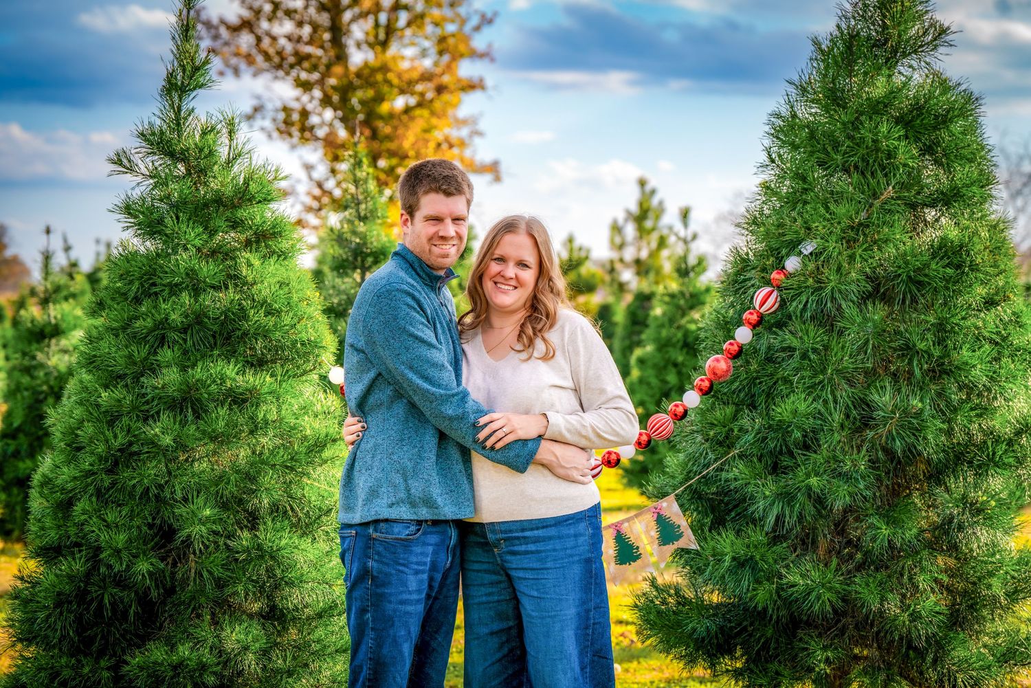 Couple takes romantic photos among evergreen trees during a sunset photo session.