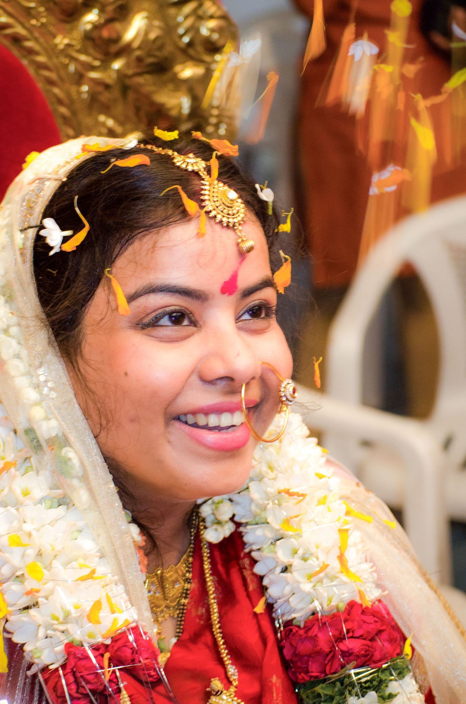 Traditional Indian bride wearing red and gold attire with floral garlands.
