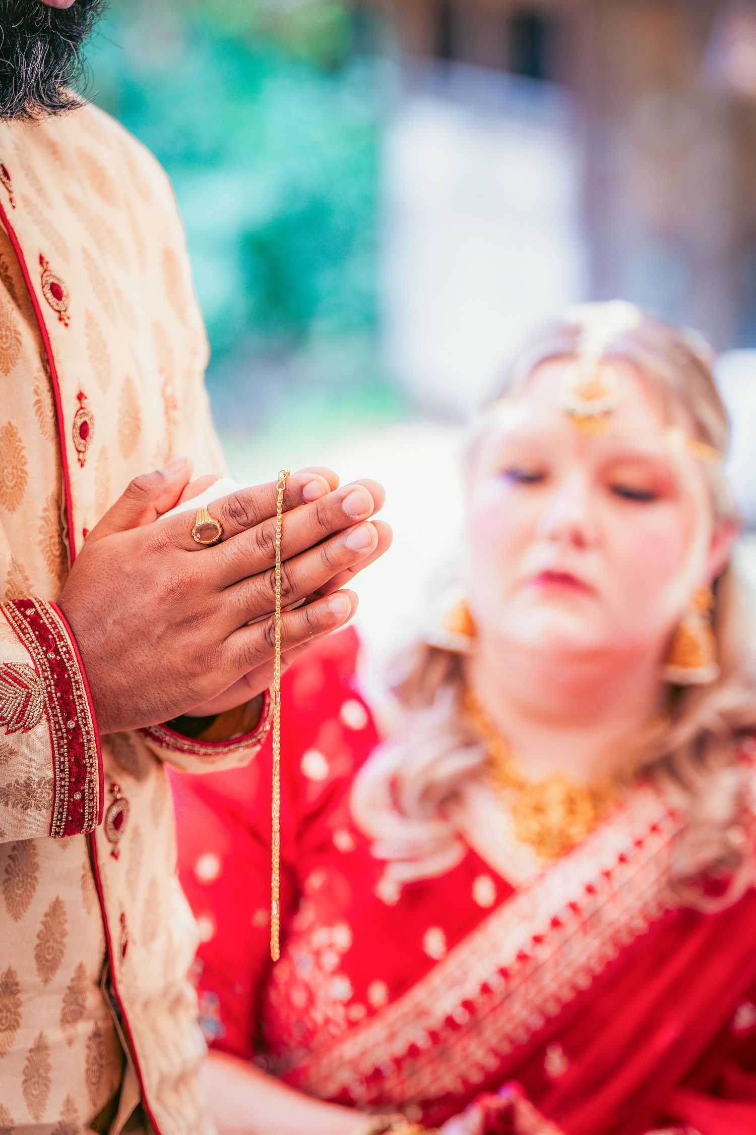 Close-up details of traditional Indian wedding ceremony with red and gold attire and decorative elements.