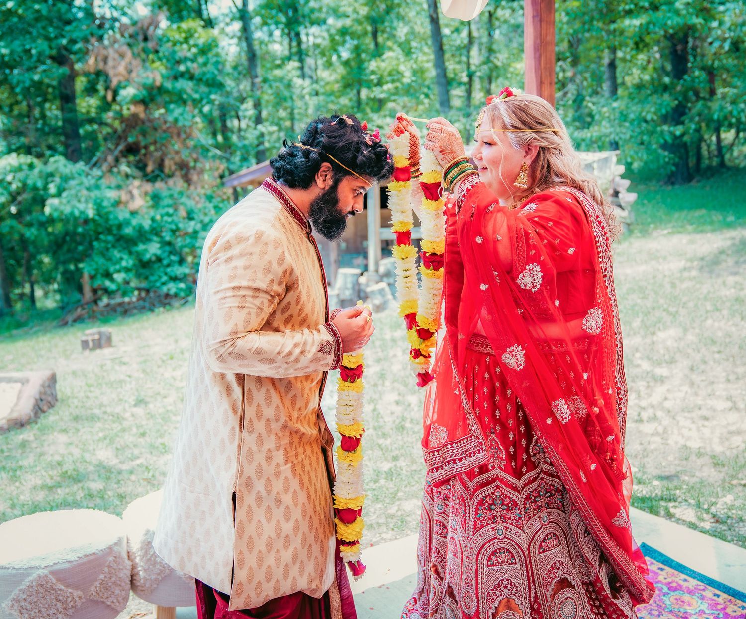 Traditional Indian wedding ceremony with vibrant red and gold attire under an outdoor tent.