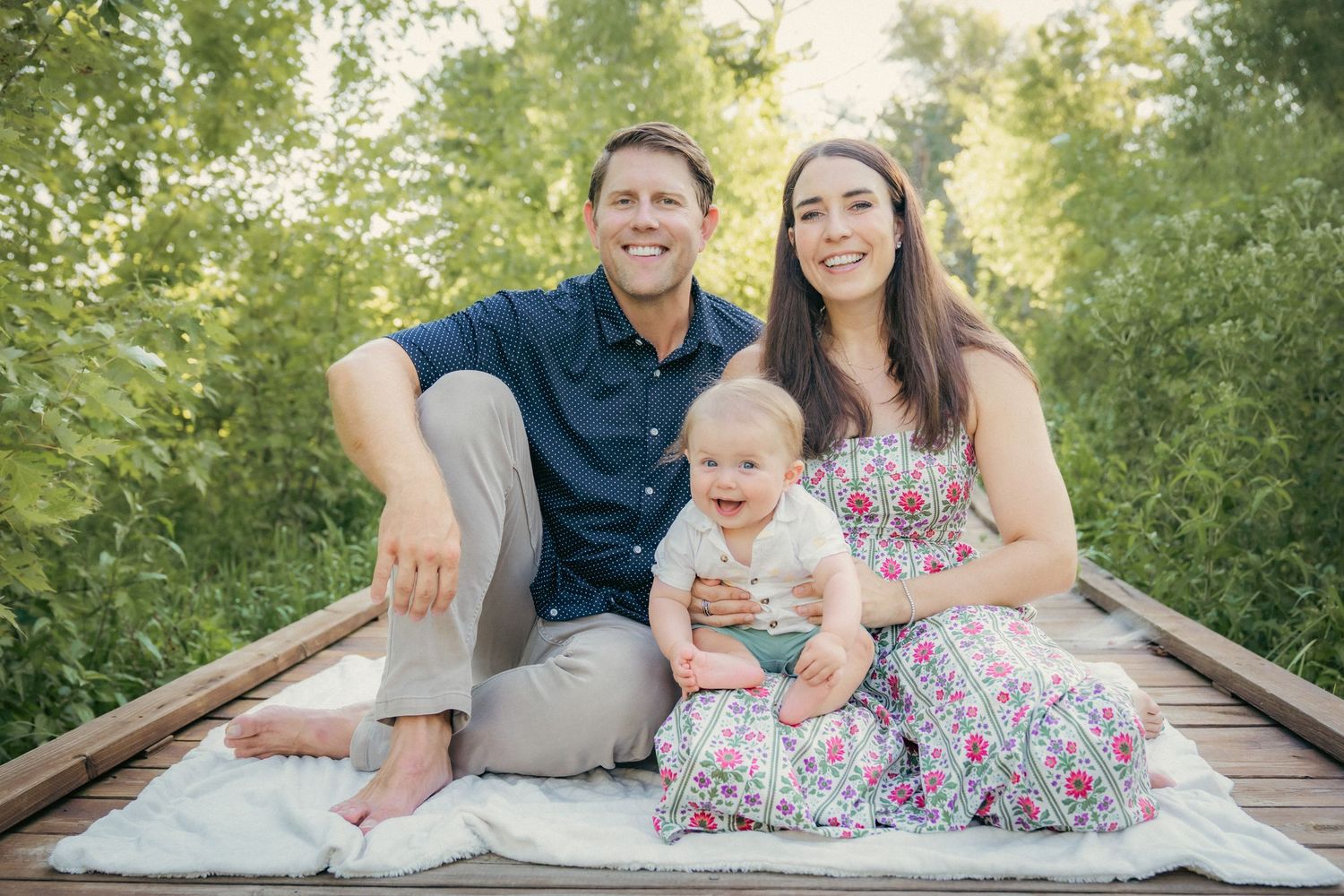 Family sitting together on wooden bridge during golden hour photoshoot.