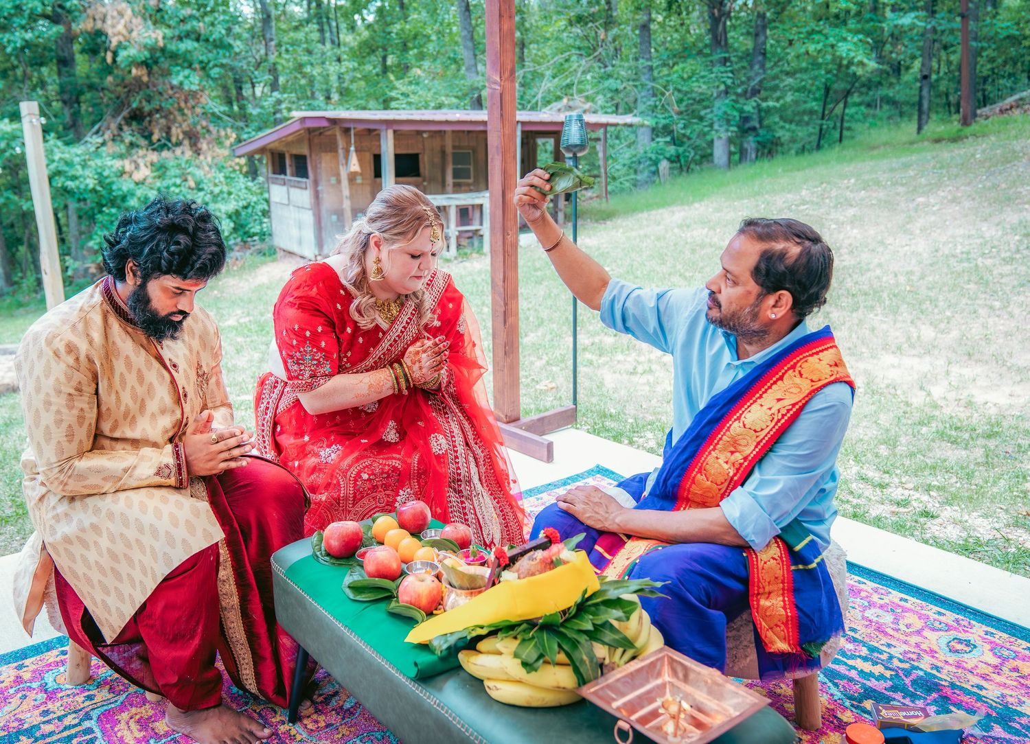 An outdoor Indian wedding celebration with guests participating in traditional customs on decorated patio.