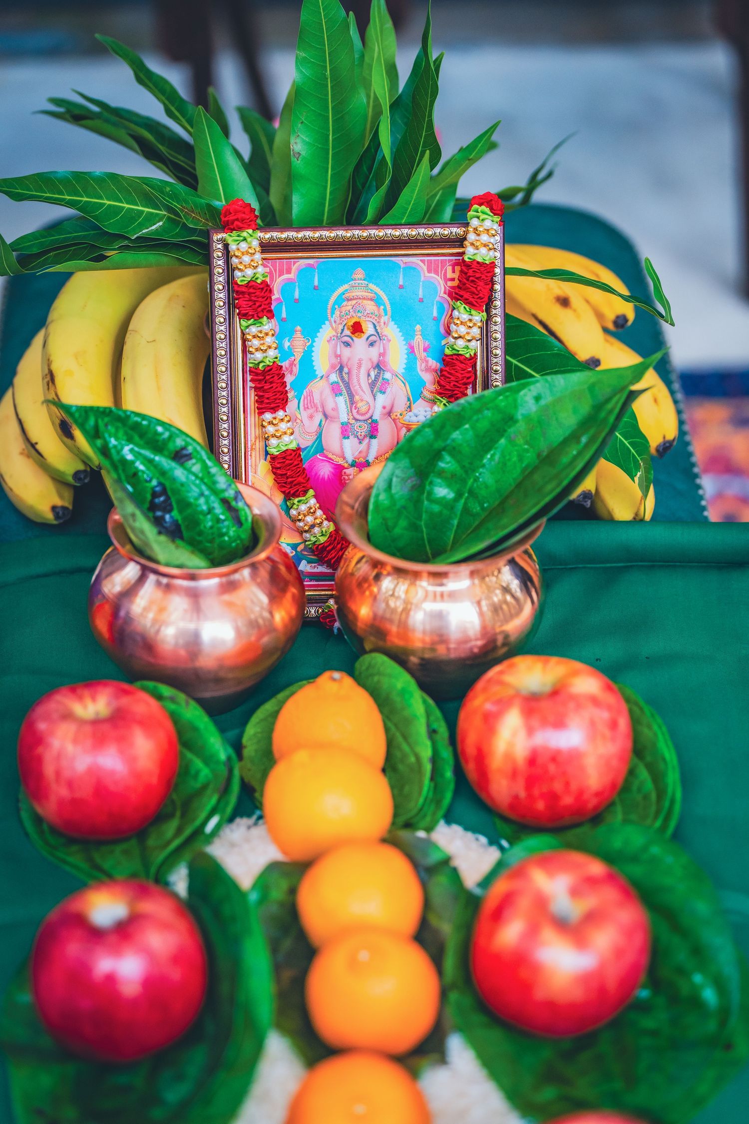 Traditional Hindu wedding altar with fresh fruits, flowers and Ganesh deity frames.