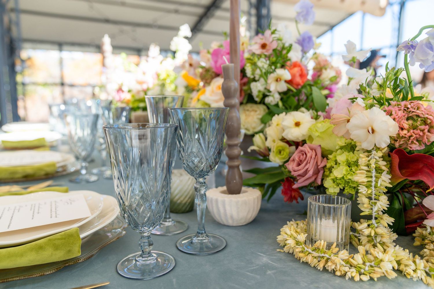 Elegant table settings with glassware and floral arrangements at wedding reception.