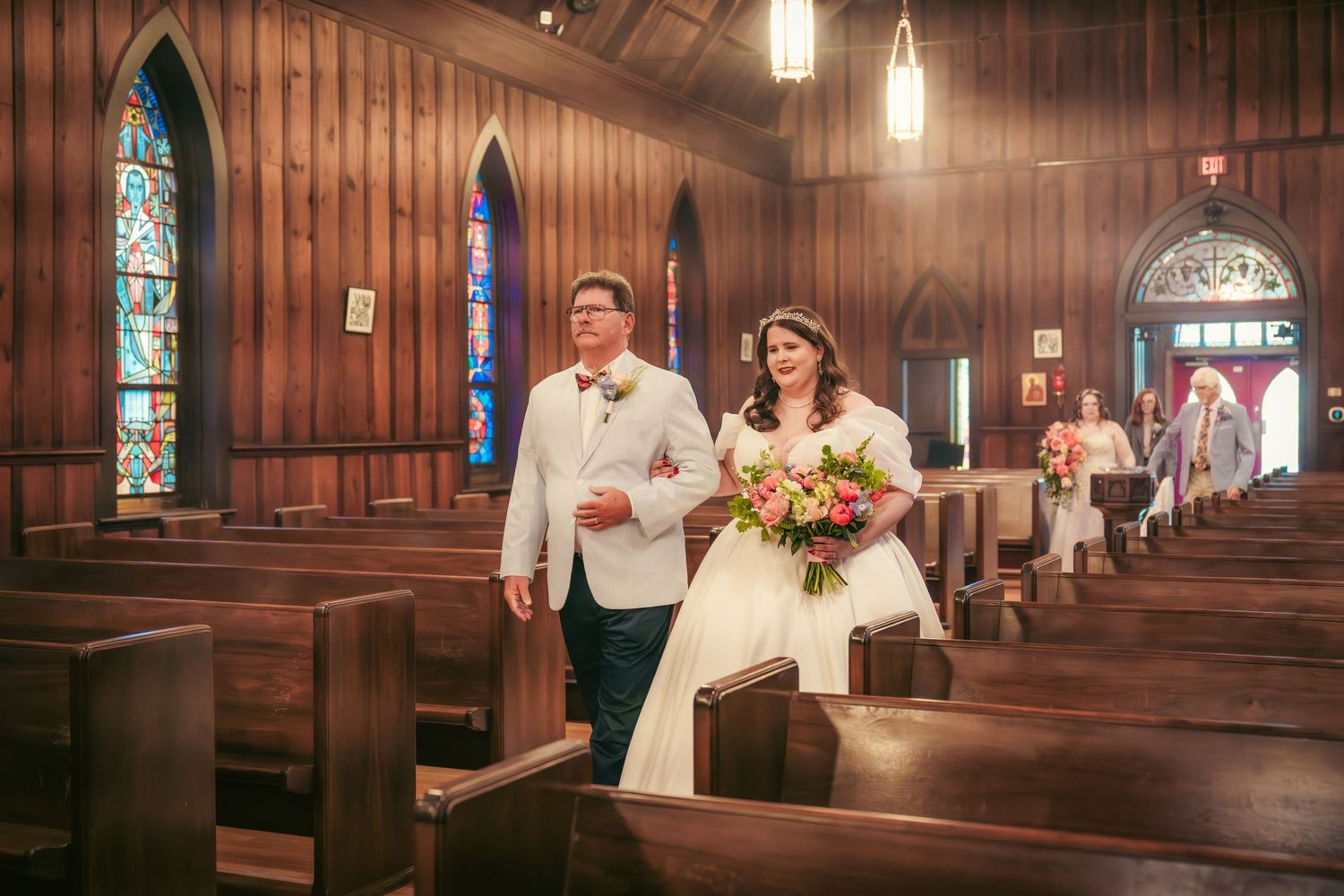 Church interior with stained glass windows and wooden pews during a wedding ceremony.