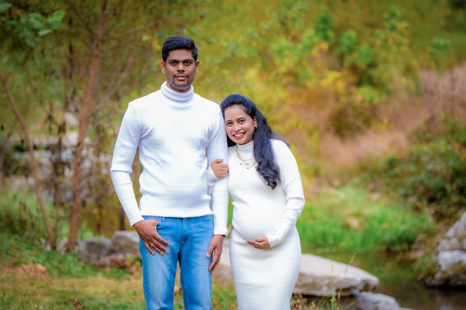 Casual outdoor maternity photoshoot featuring couple in white and denim outfits.